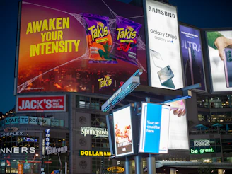 Bright digital billboards illuminate a city square at night.