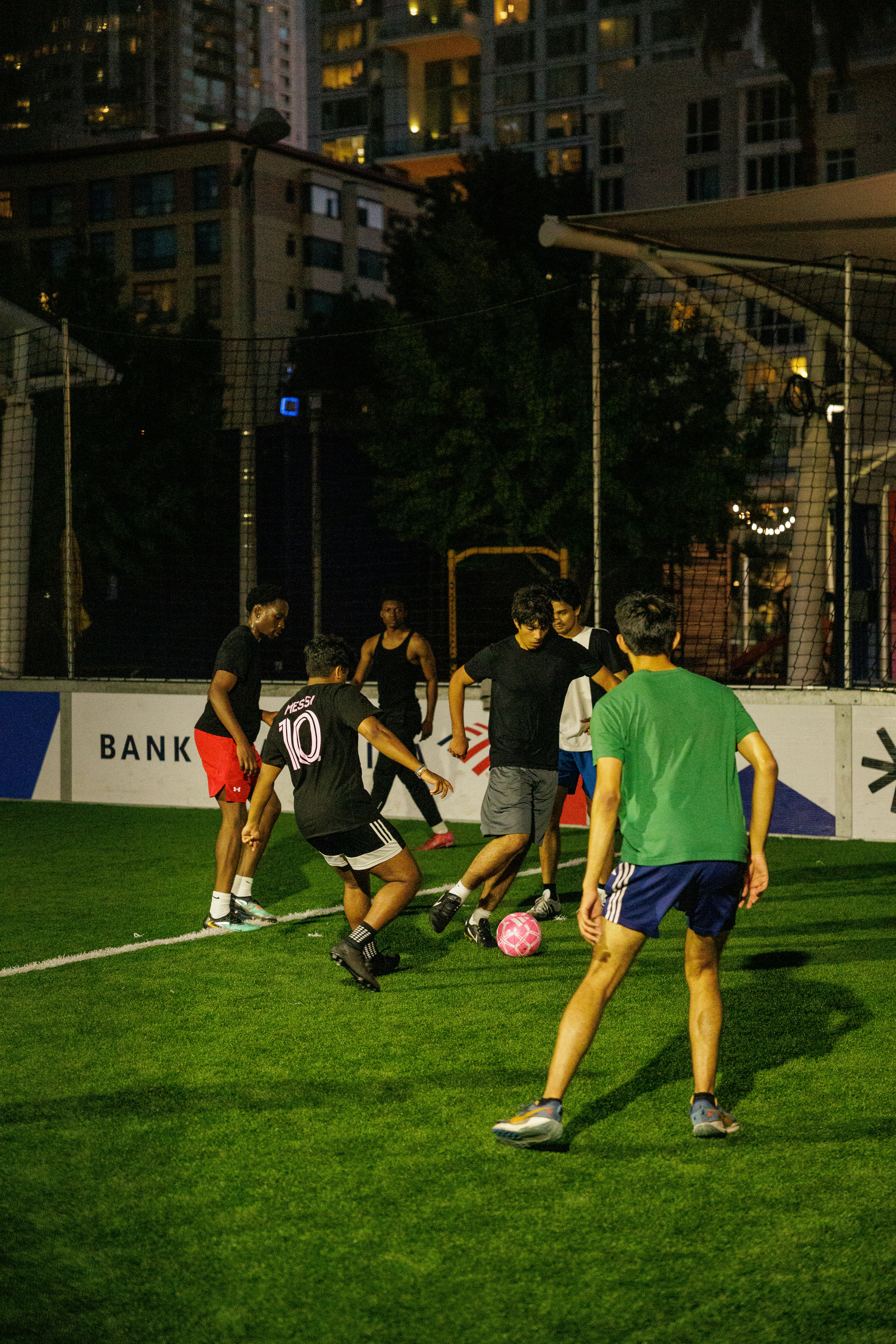 A group of people playing soccer on an artificial turf field at night