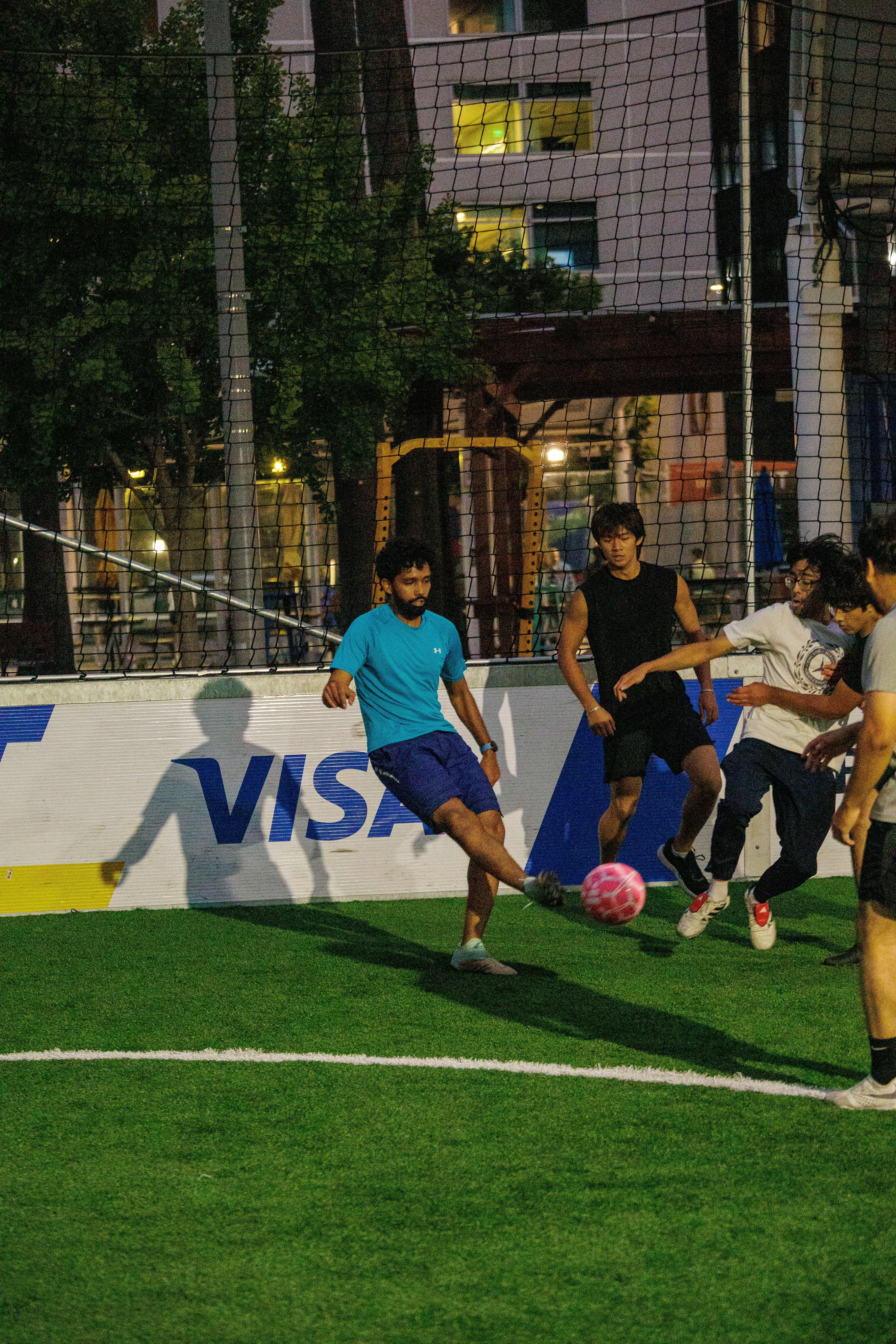 A man in a blue shirt kicking a pink soccer ball on a field