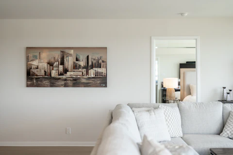 Contemporary living room featuring cityscape artwork and a light sofa