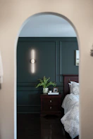 Bedroom with dark green wall and modern light through archway
