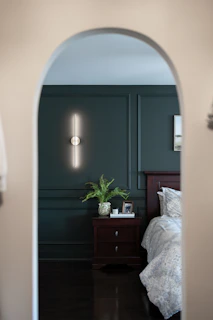 Bedroom with dark green wall and modern light through archway