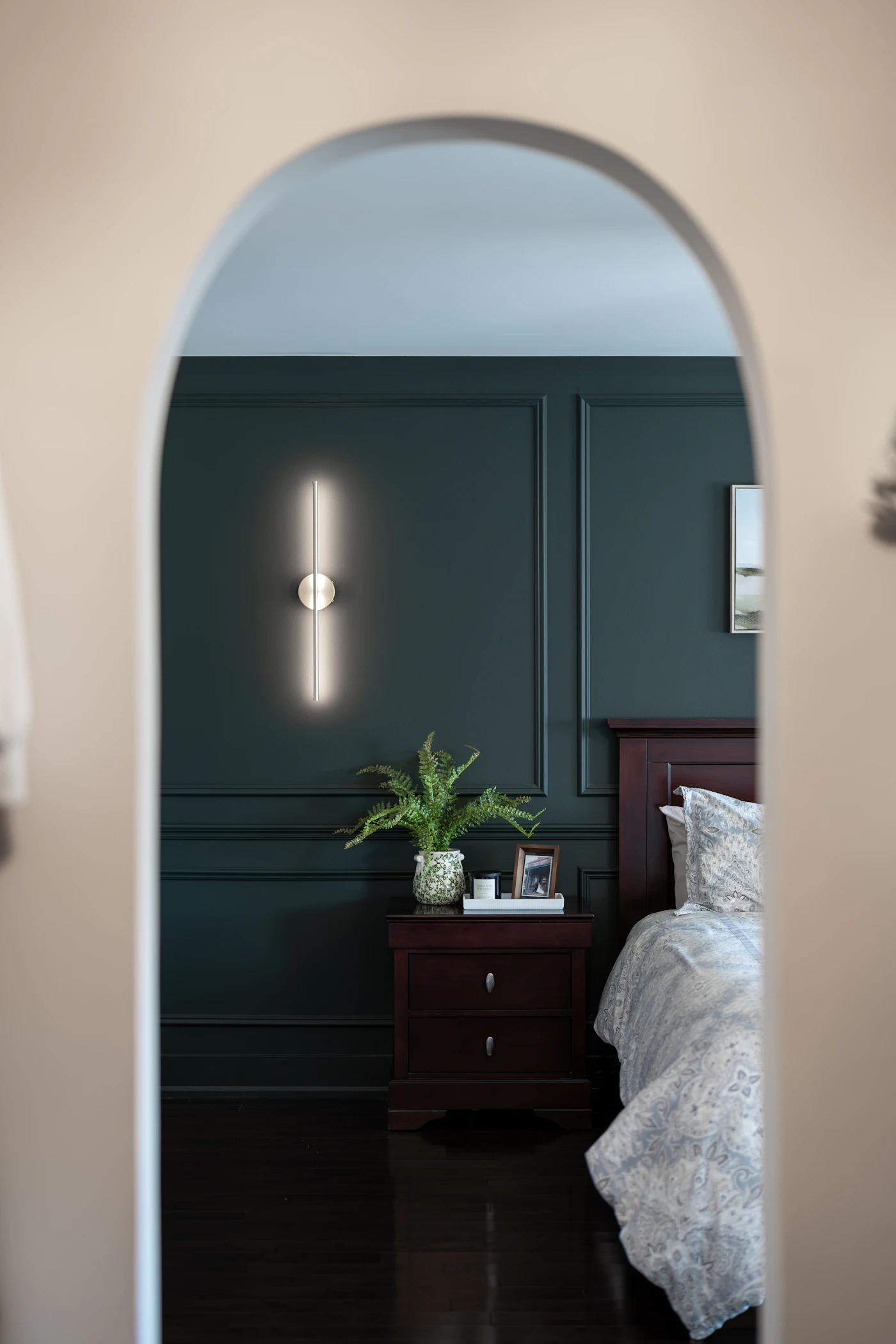 Arched doorway with a wall sconce and muted green door (placeholder photograph)