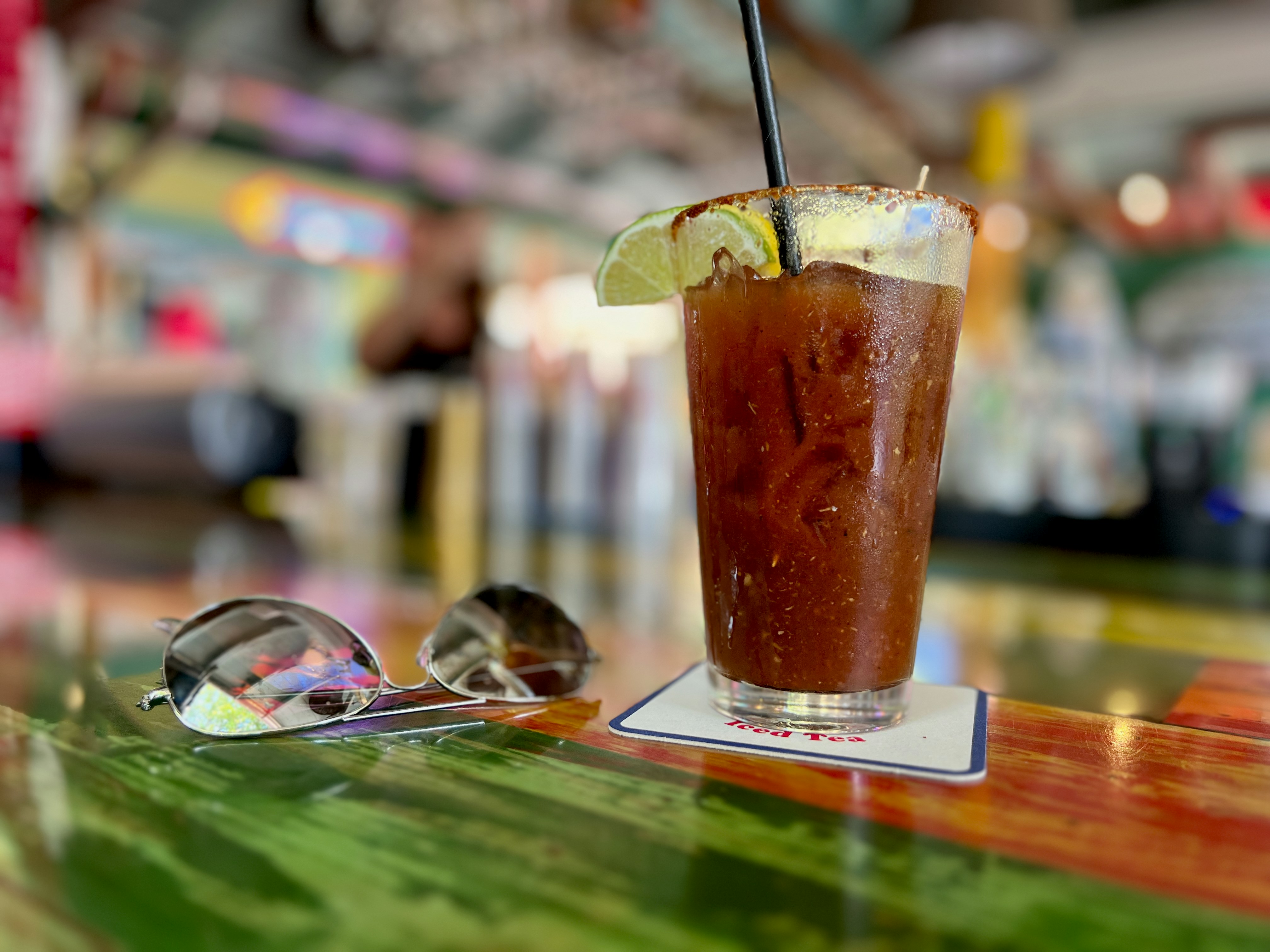 Un cocktail bloody mary con occhiali da sole su un bancone vivace