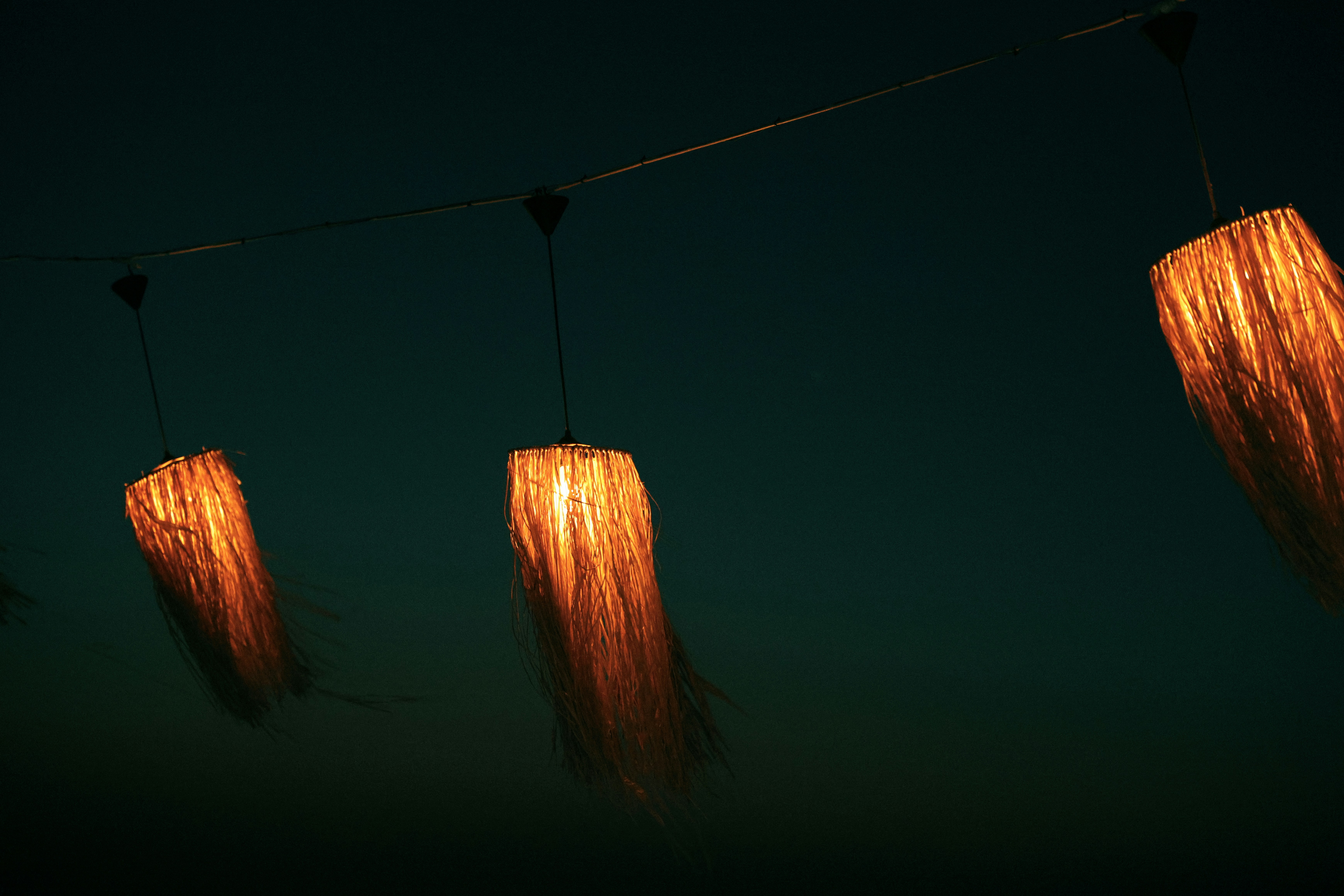 Three rustic lamps emitting warm light in darkness