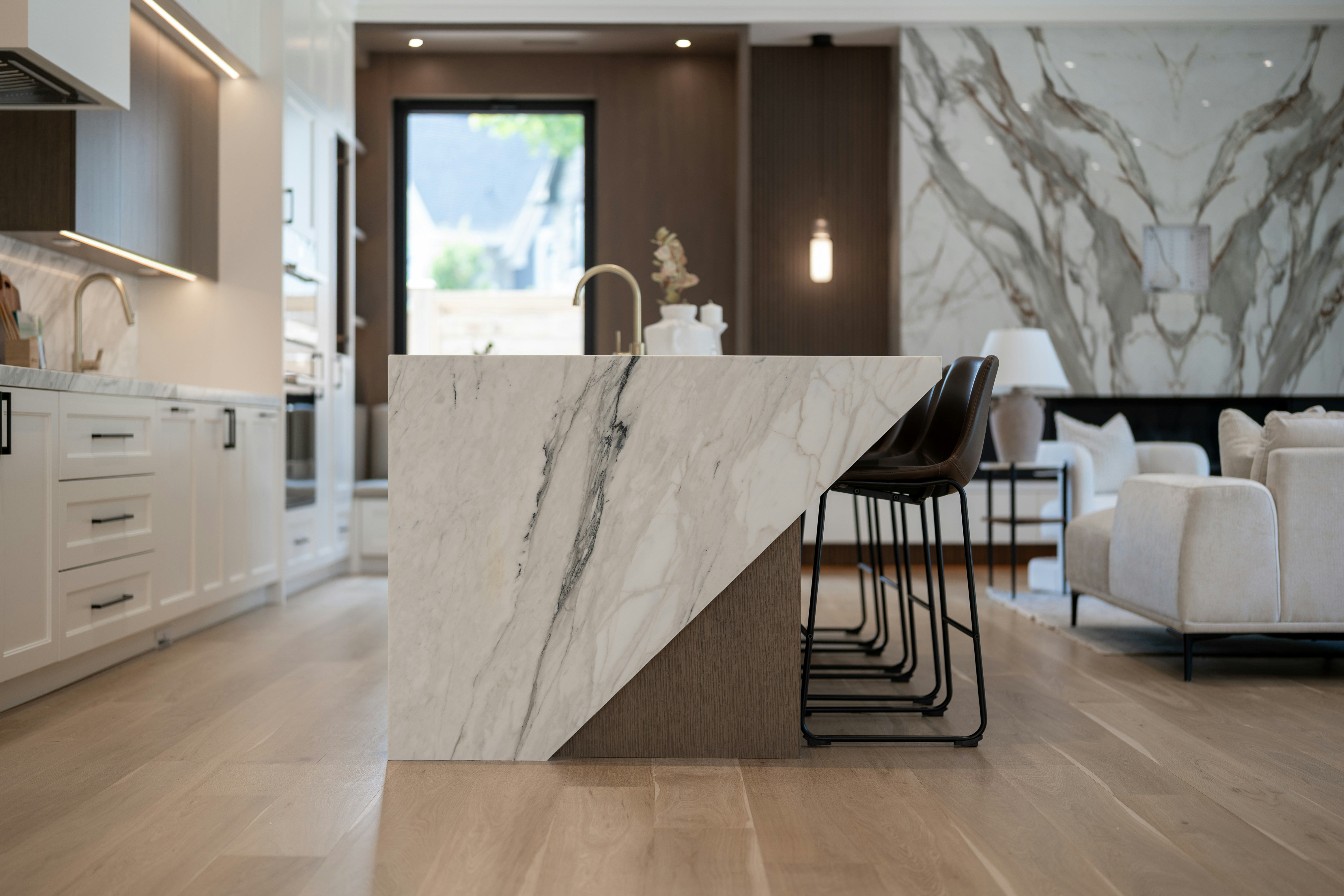 Modern kitchen with a large marble island and bar stools.