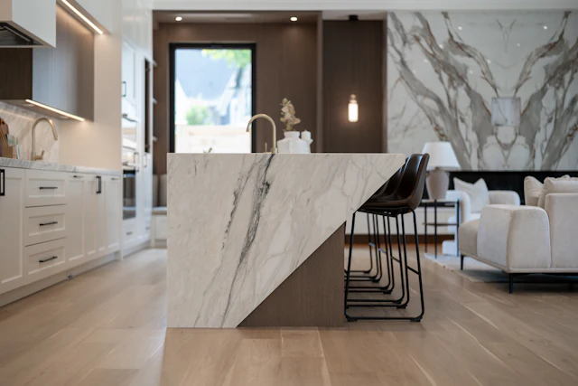 Waterfall island in bold-veined white marble in front of a matching marble wall