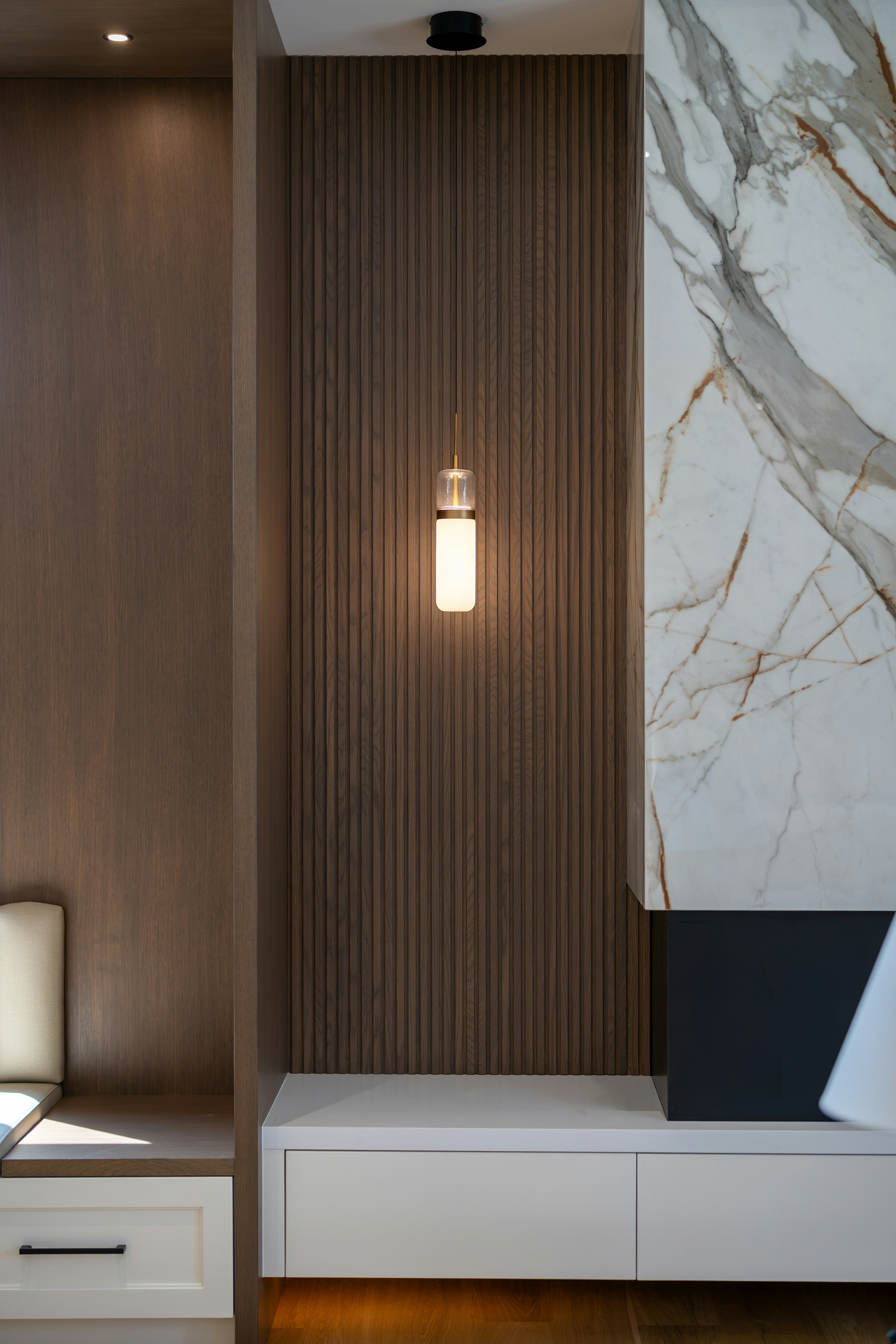 Modern interior with wooden slats, pendant light, and marble wall.