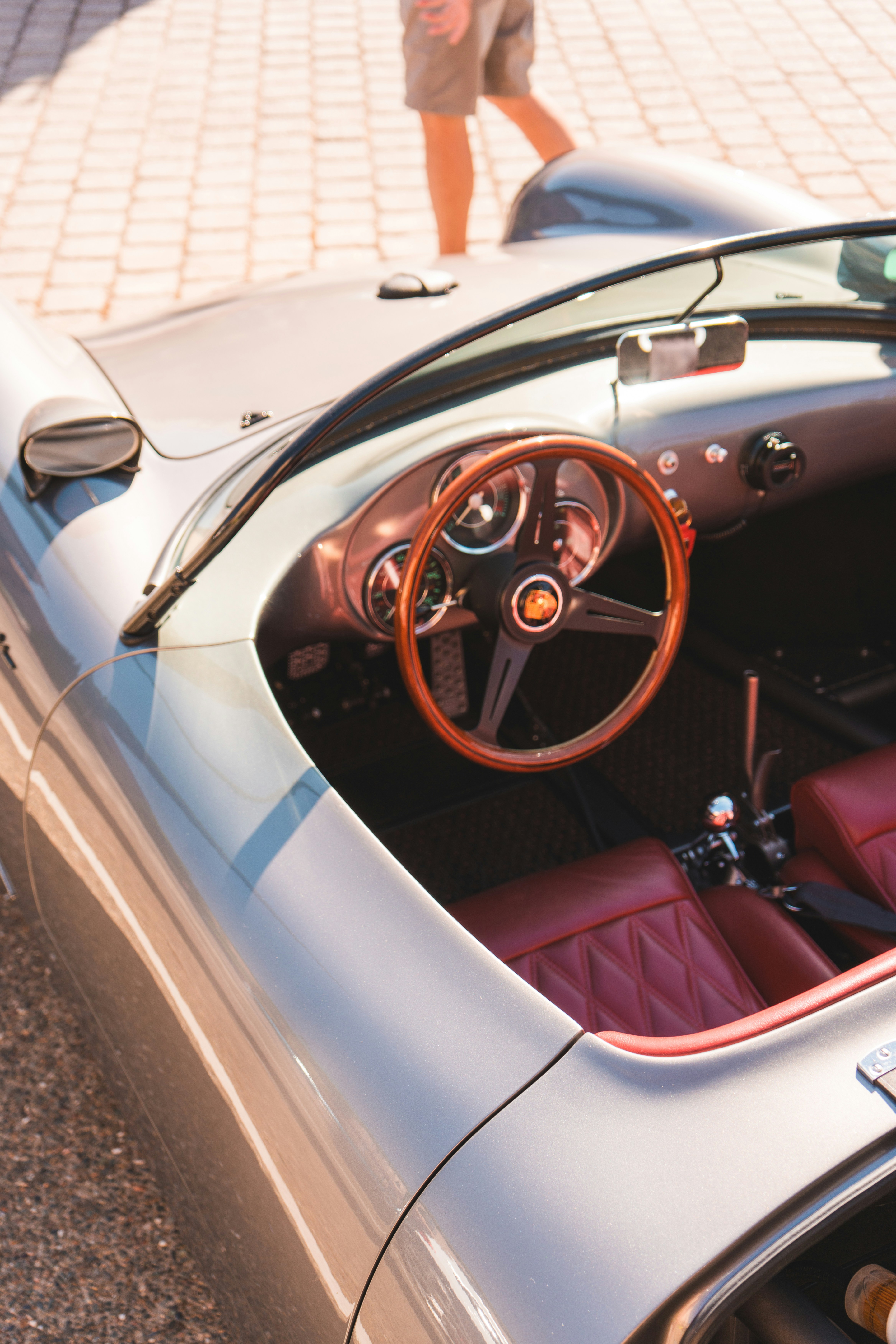 Carro vintage prateado com volante de madeira e interior vermelho