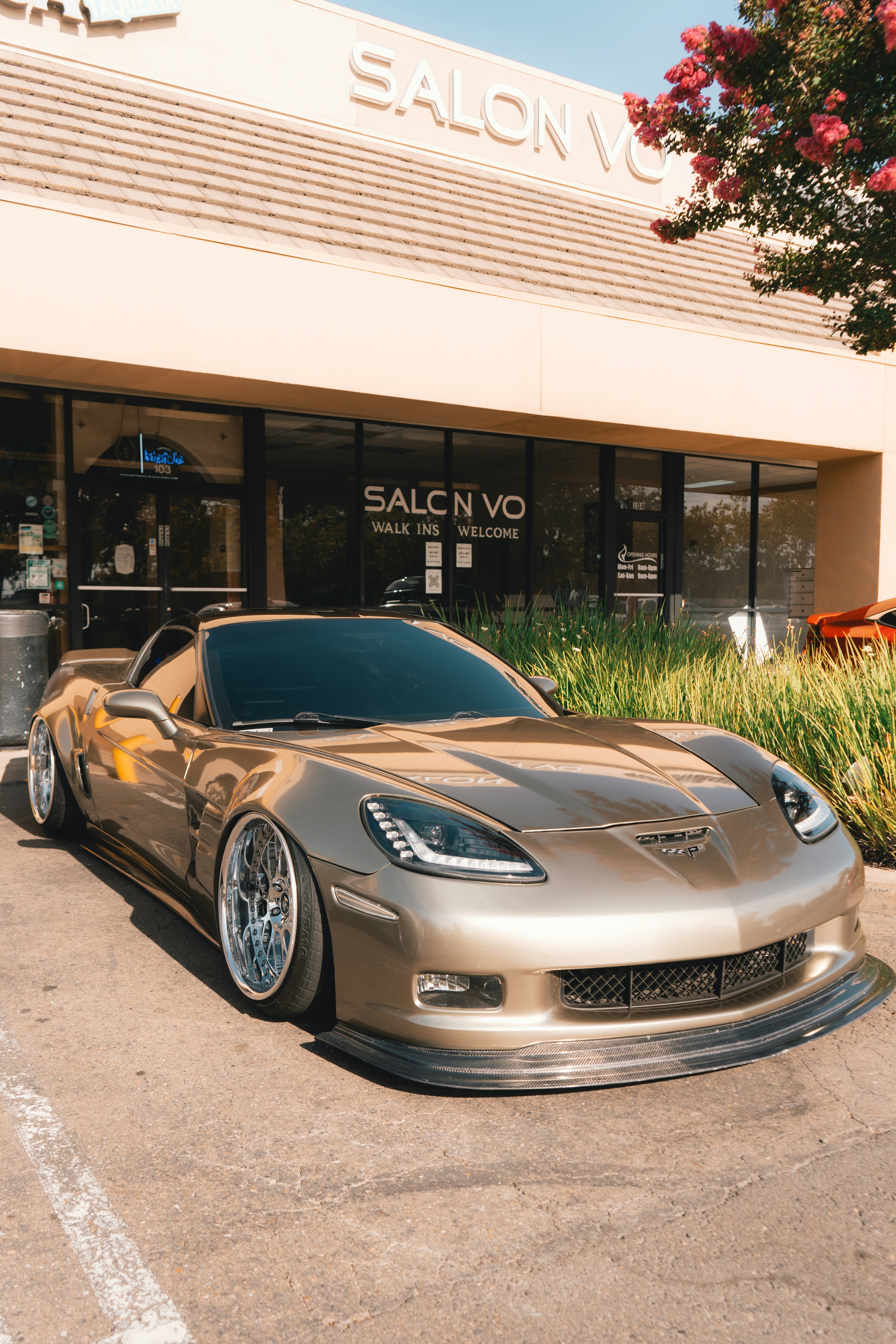 Um Chevrolet Corvette dourado estacionado em frente ao voo do salão