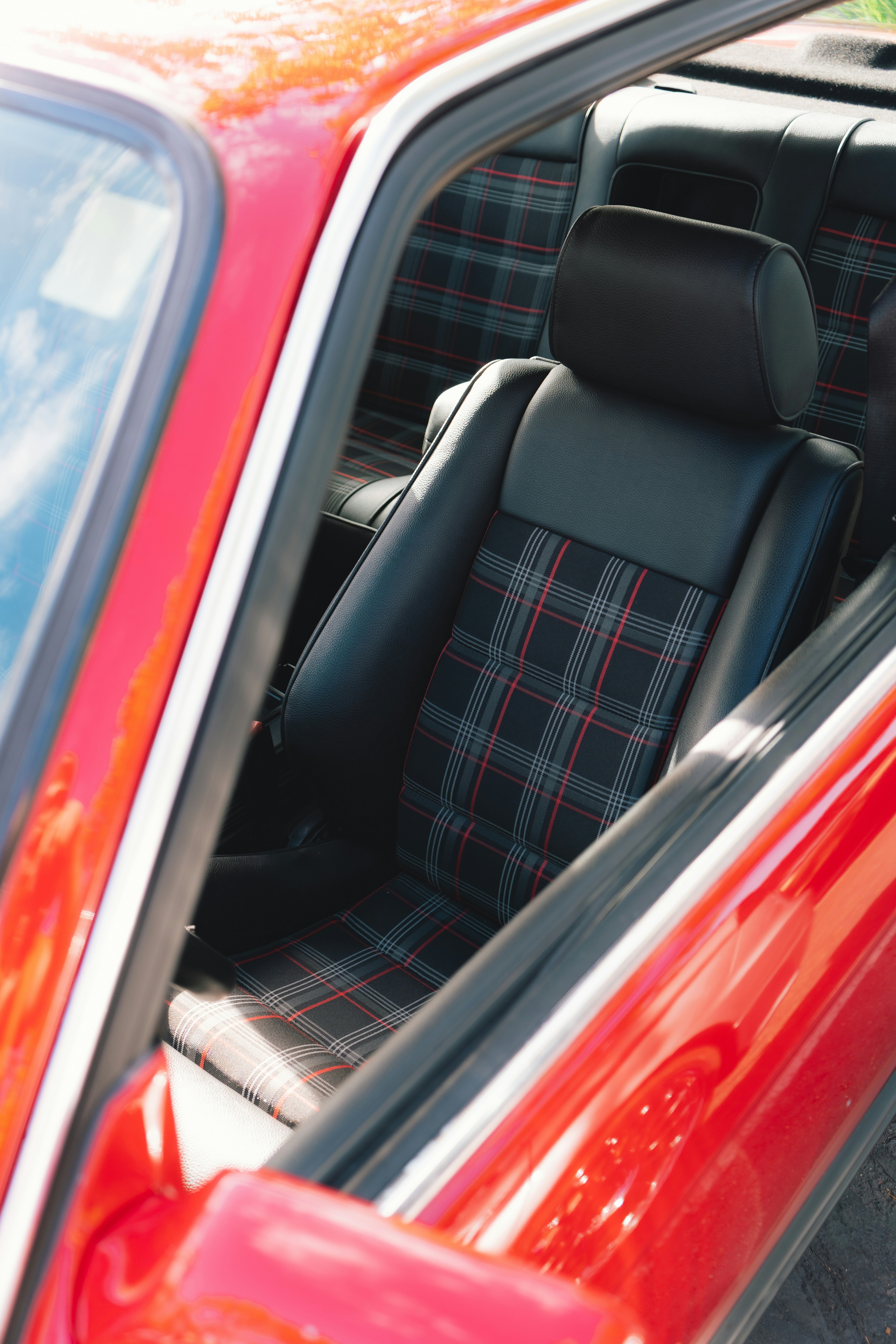O interior de um carro vermelho com banco preto e xadrez