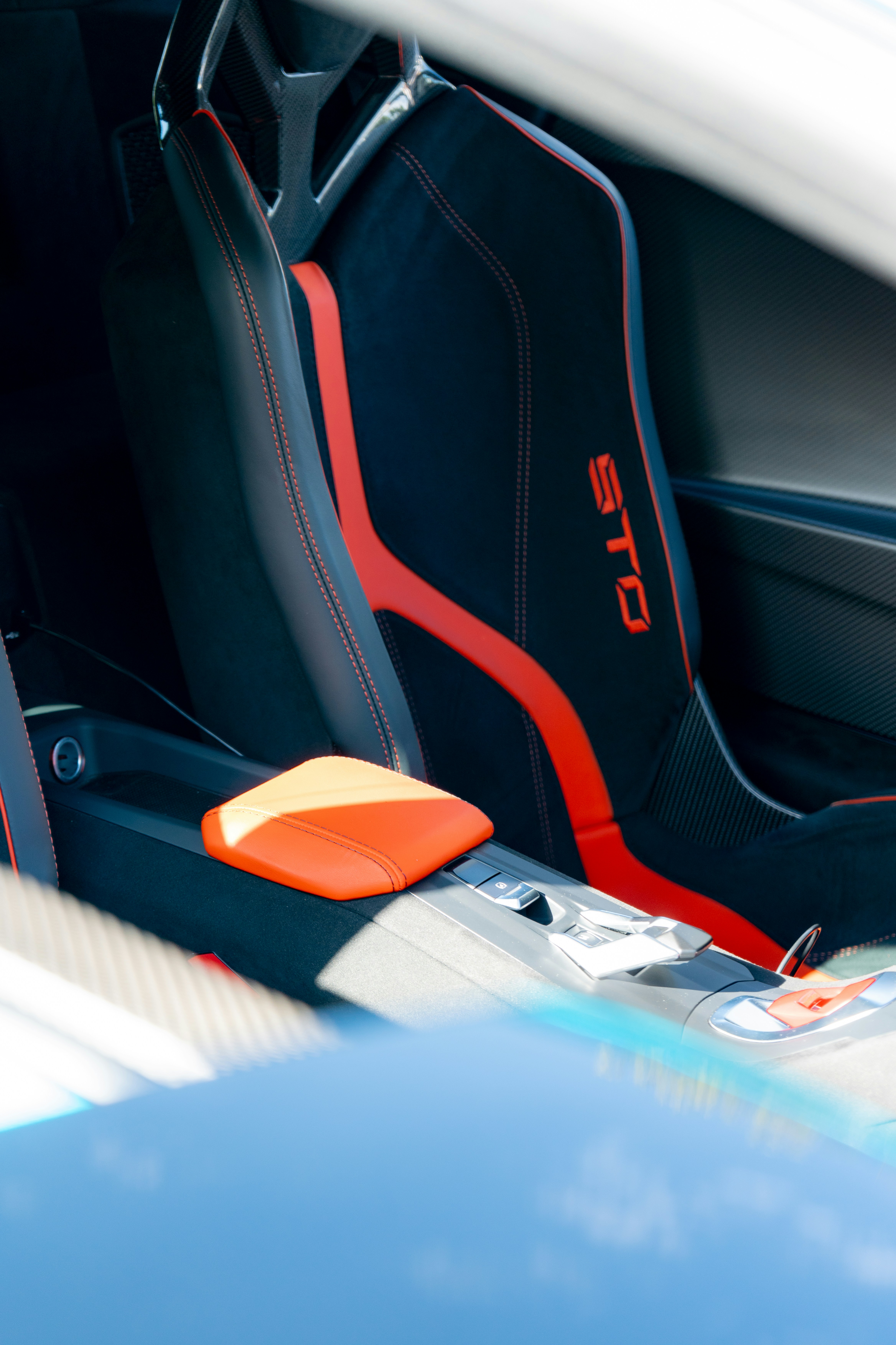 Cadeira de corrida preta com detalhes vermelhos dentro de um carro esportivo