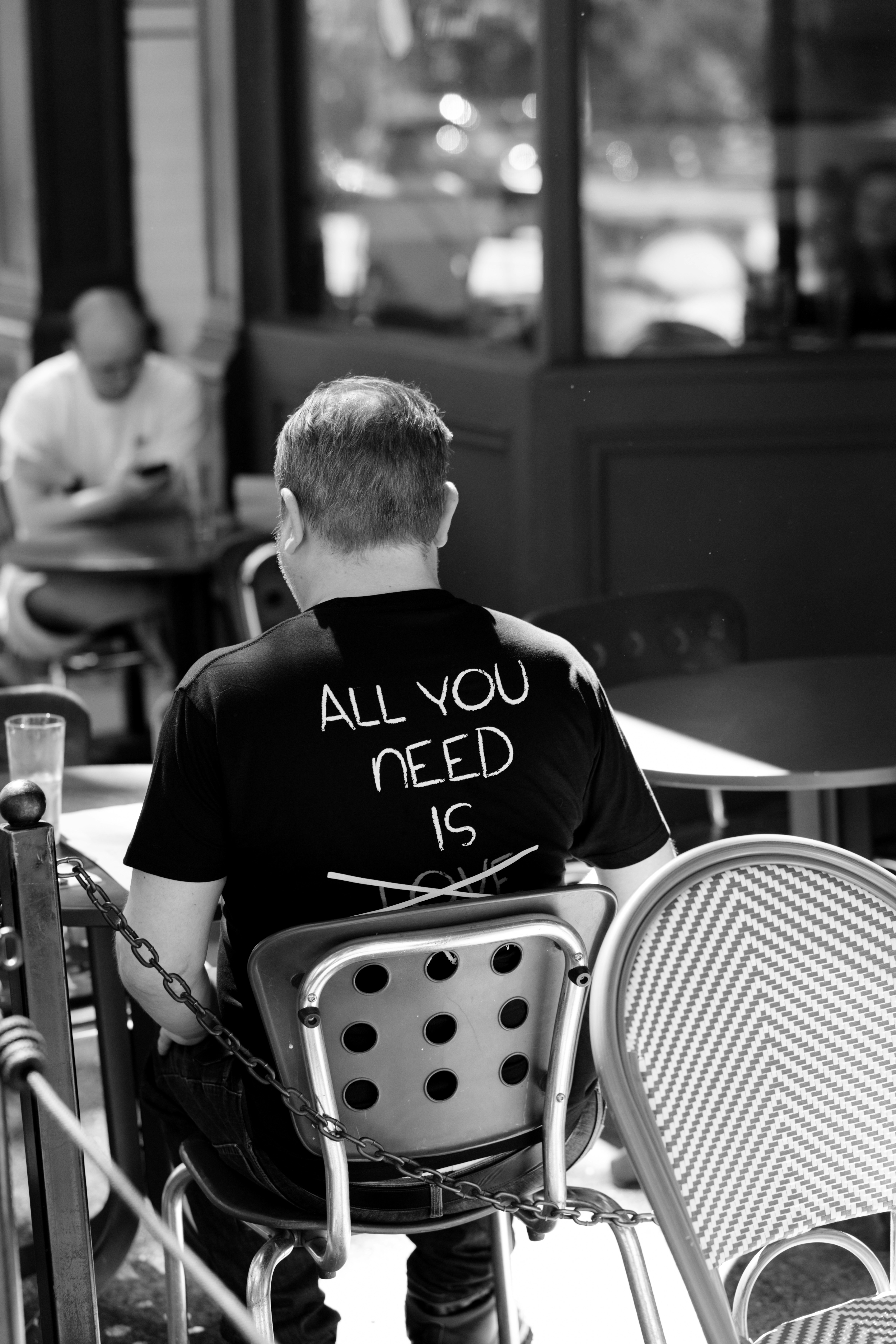 Man wearing "all you need is" t-shirt sitting at cafe