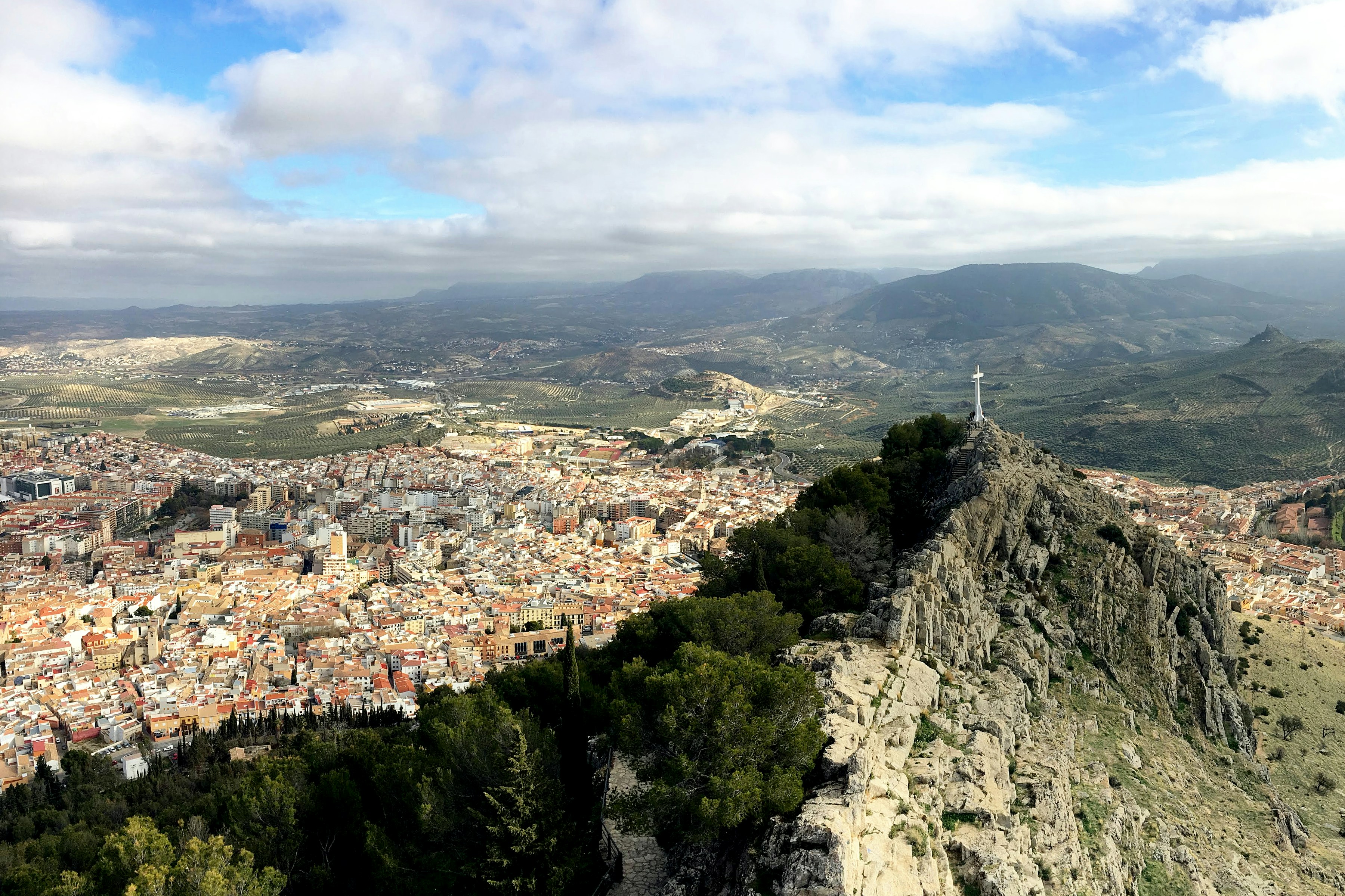Sprawling city, rocky peak with cross, and distant mountains