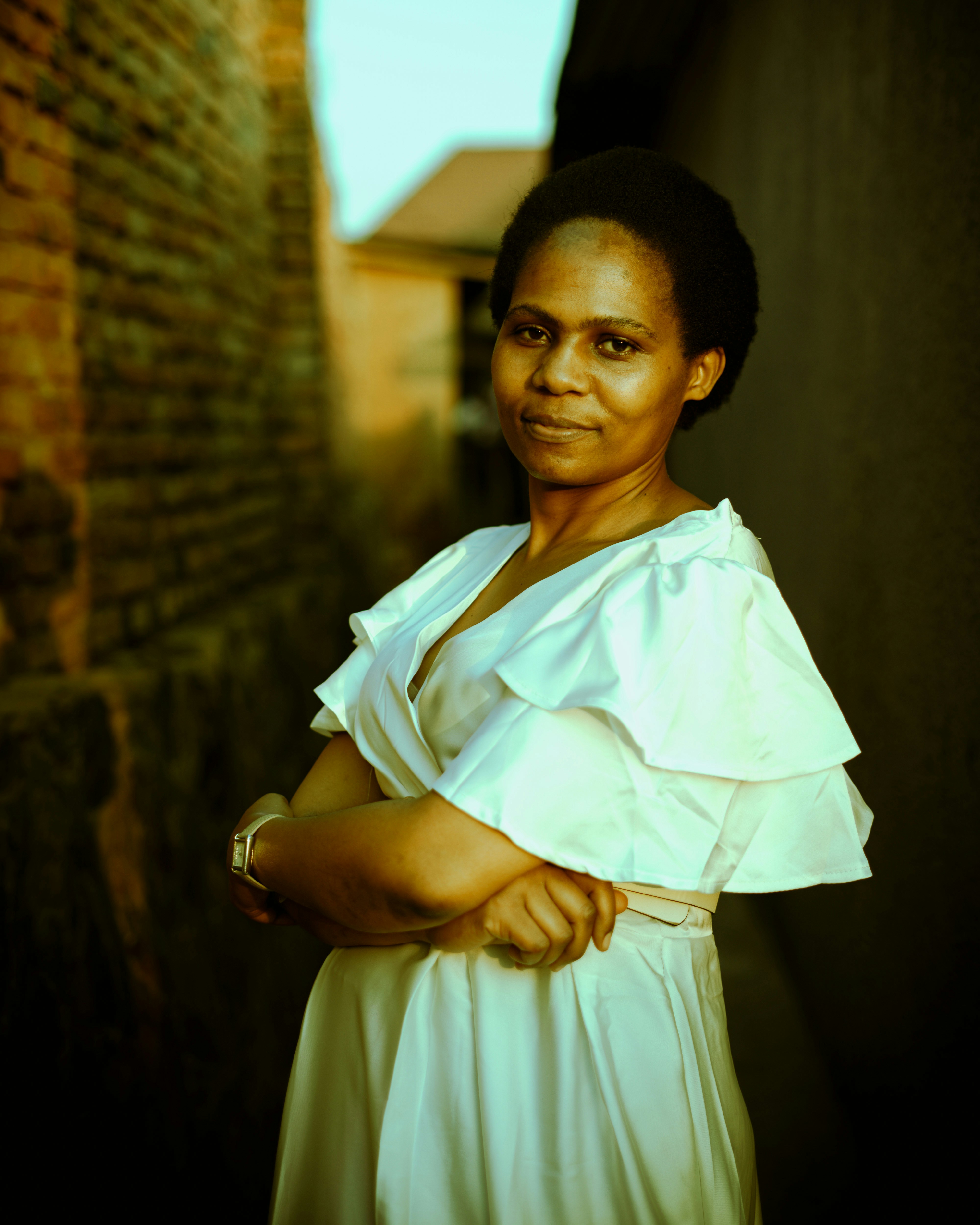 A woman in a white dress stands in an alley