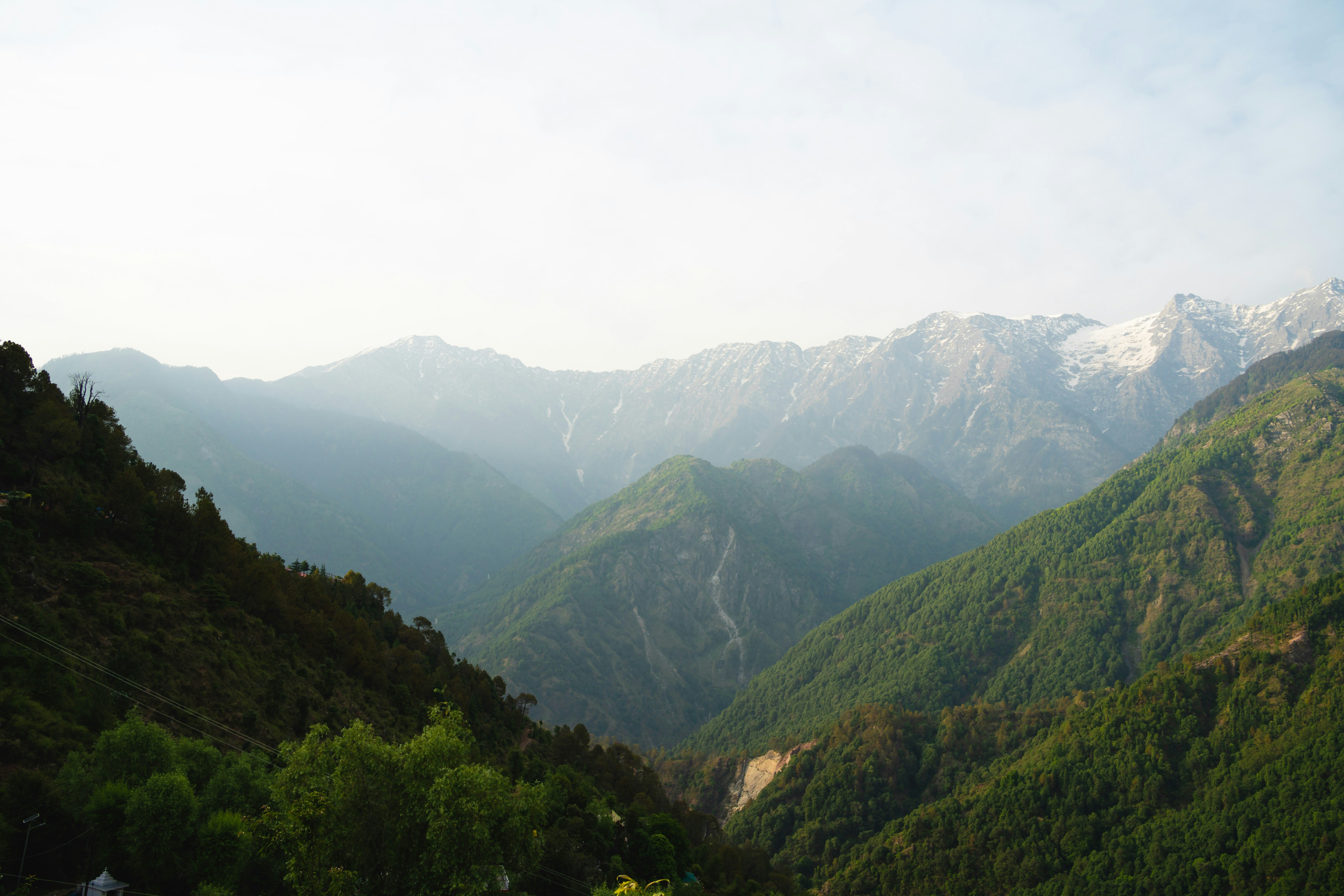 Lush green mountains and distant peaks under a bright sky.