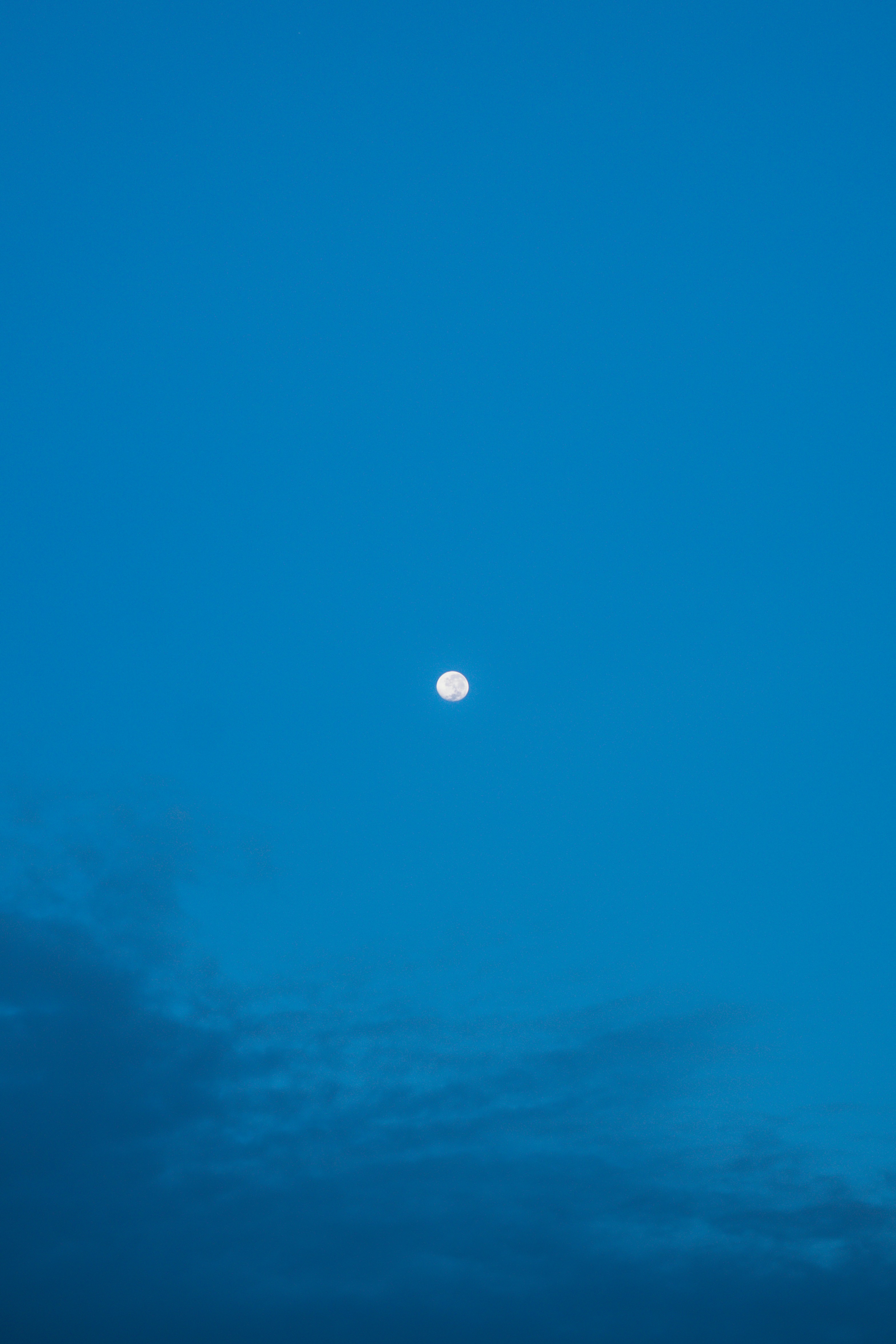 Vollmond an einem klaren blauen Himmel mit dunklen Wolken
