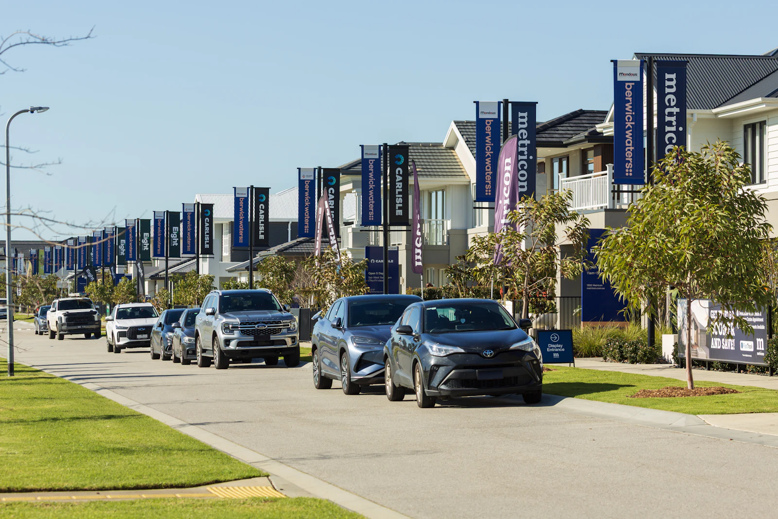 A street of newer townhomes and parked cars.