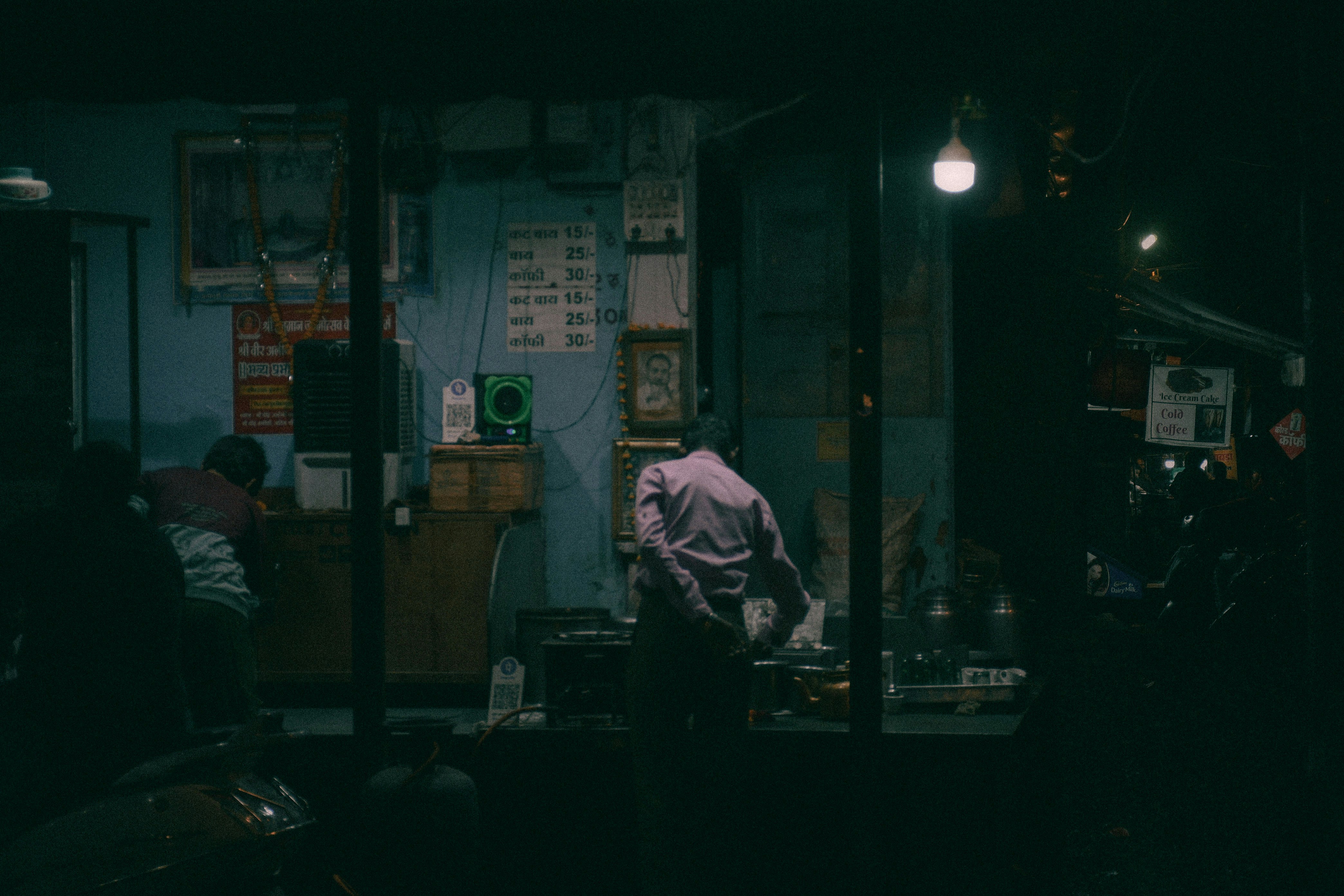 A person inside a dimly lit storefront at night