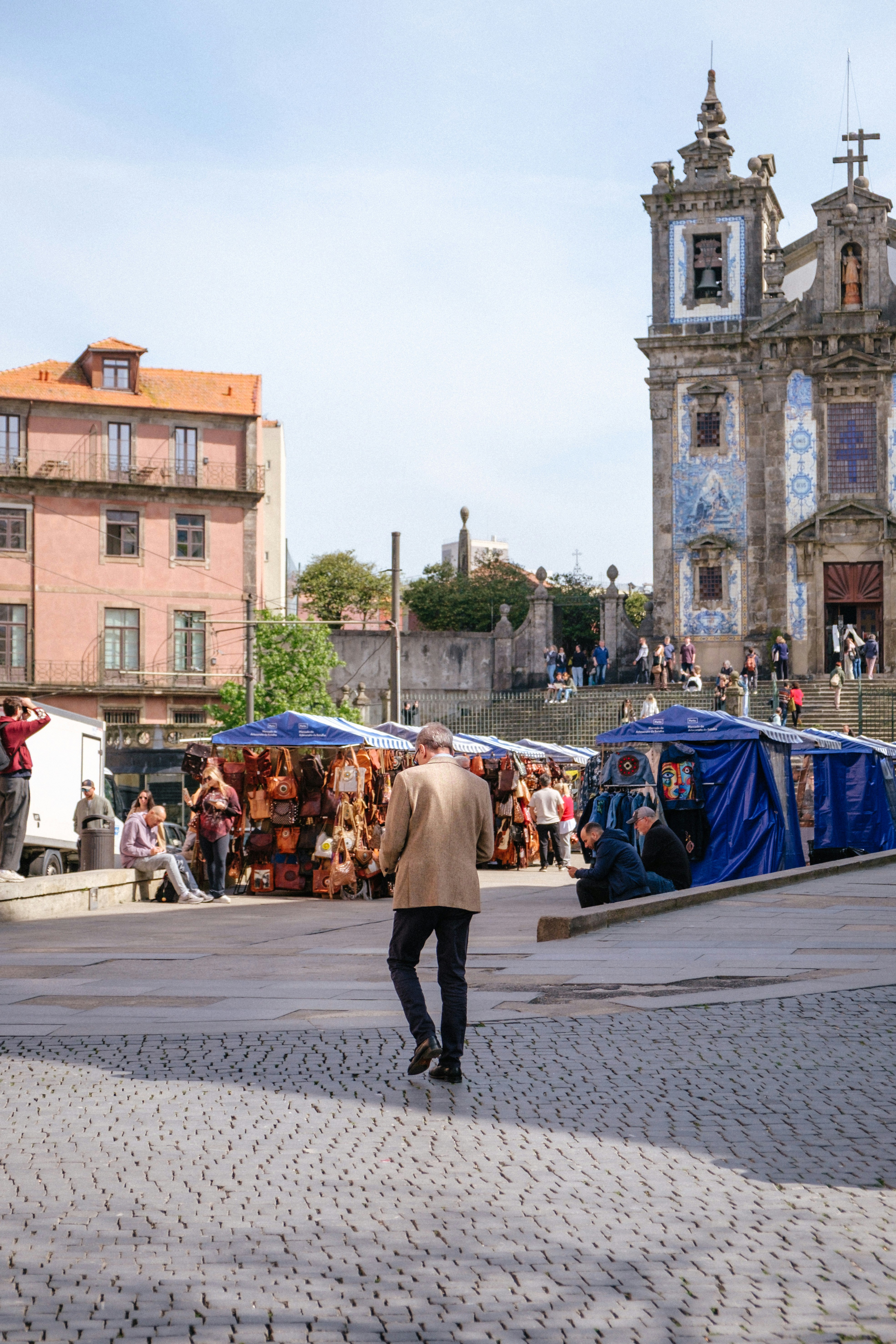 Man walks past market stalls by tiled church