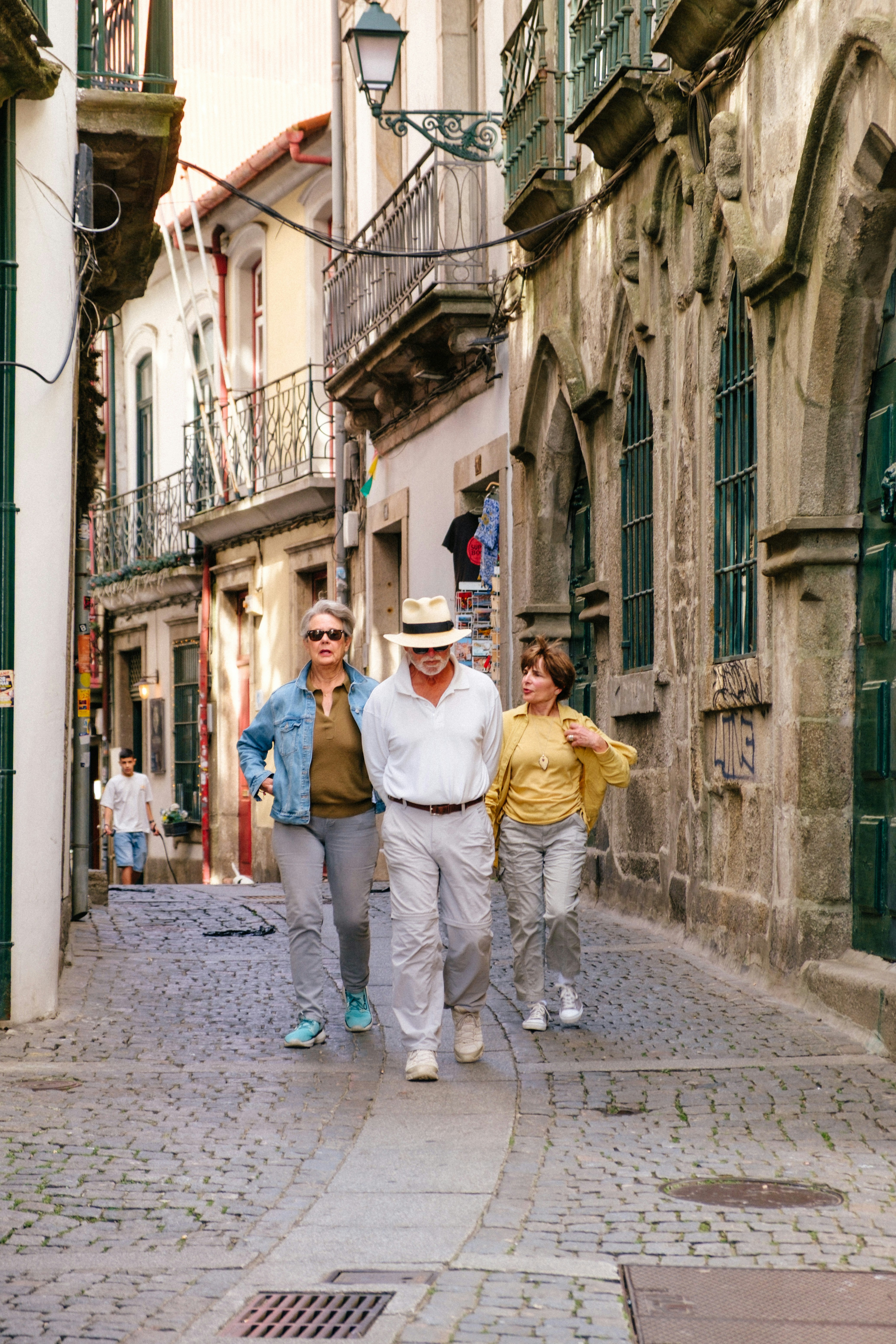 Three adults walking on a narrow cobblestone street
