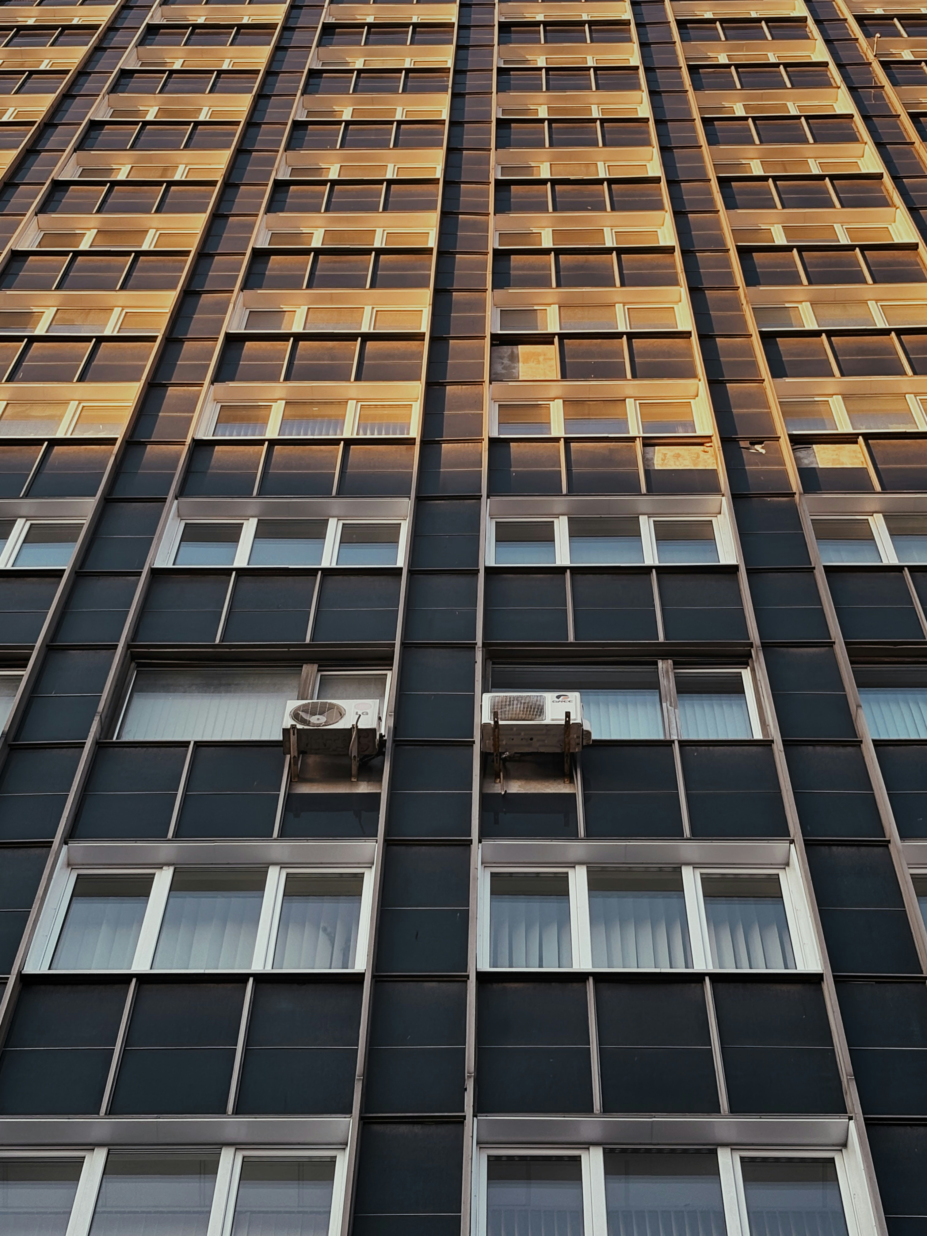 Tall building facade with many windows and air conditioners