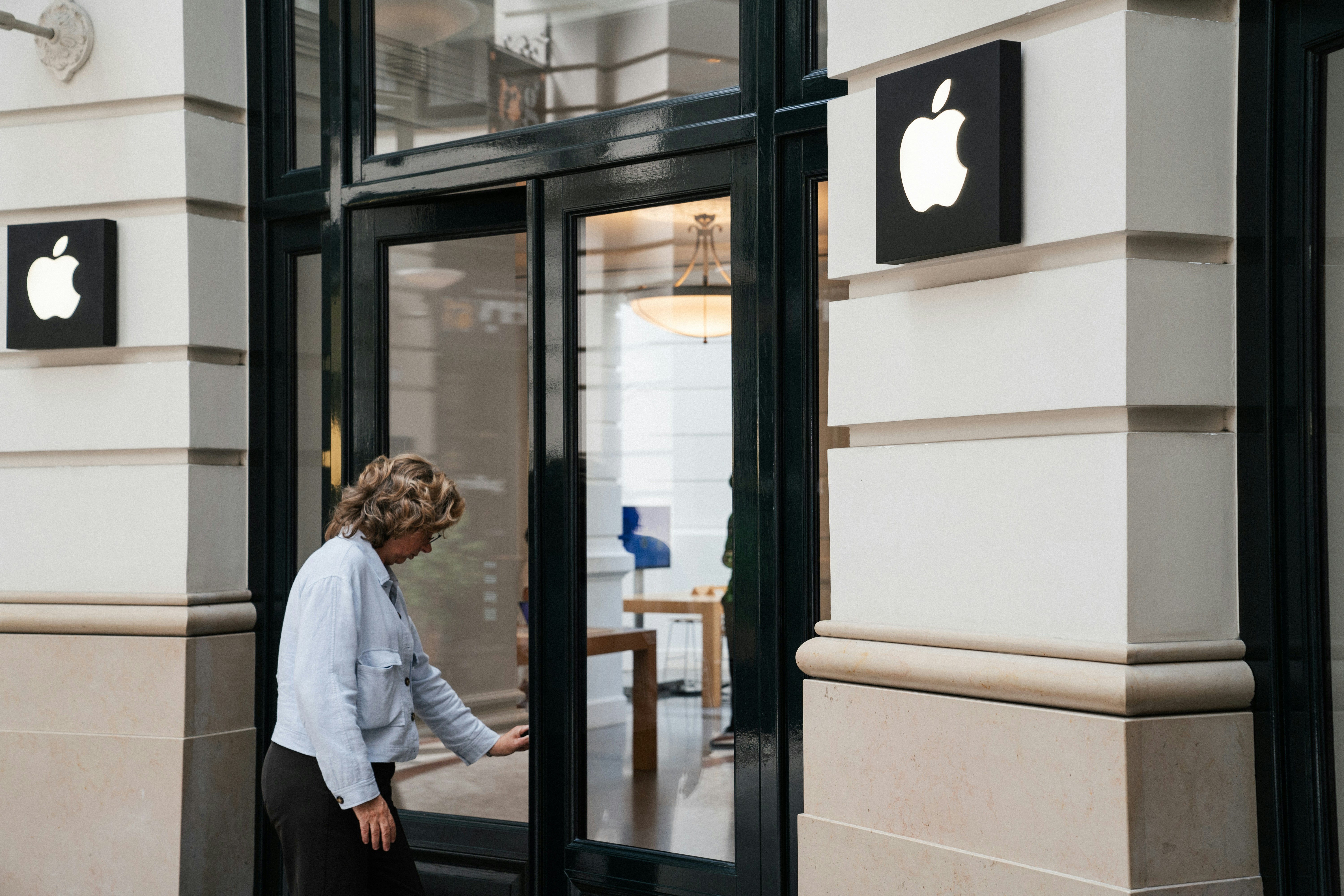 アップルストアのガラス扉を開ける人。