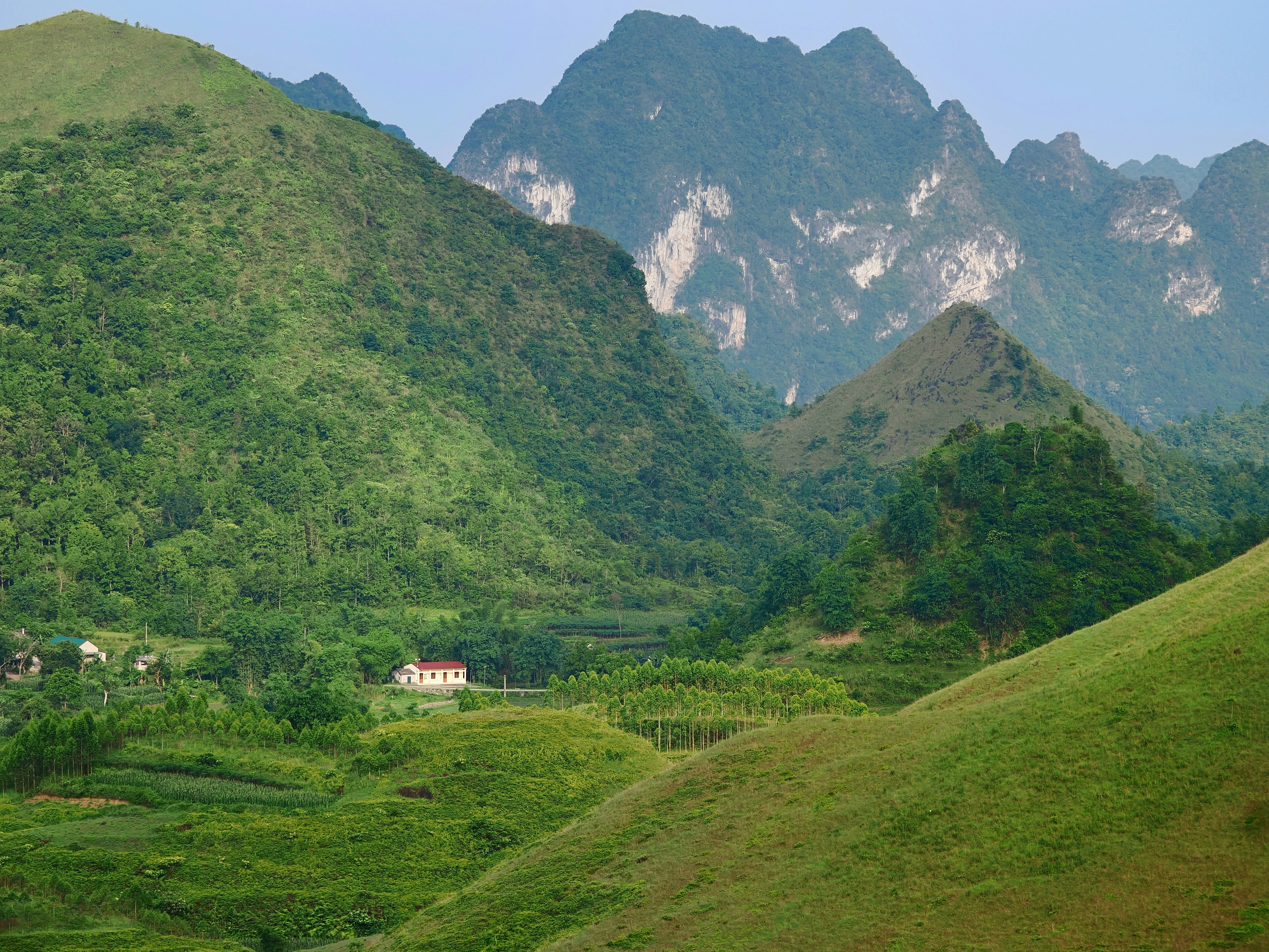Green mountains and rolling hills with a small house.