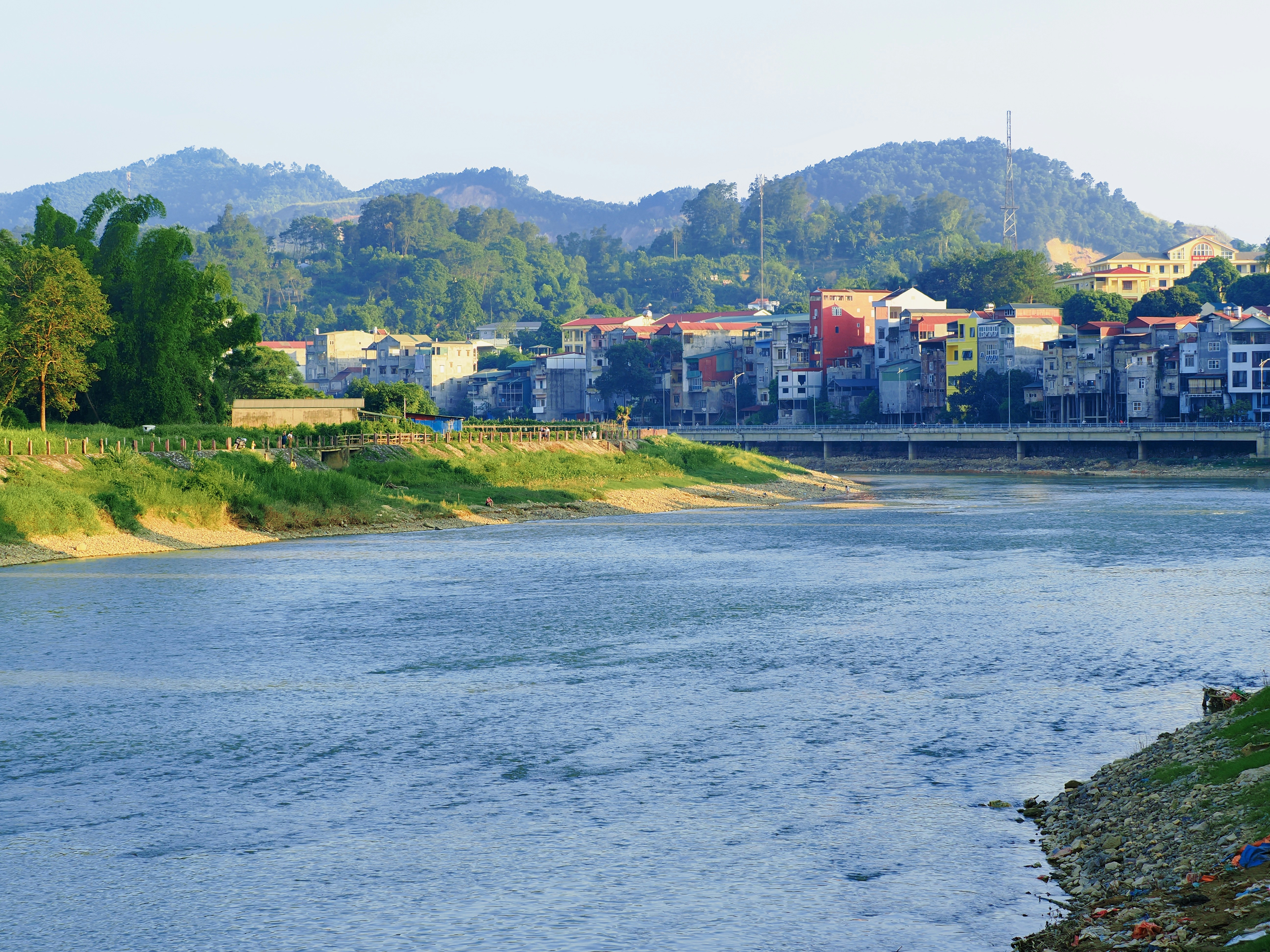 Scenic river flows past a town and green mountains.