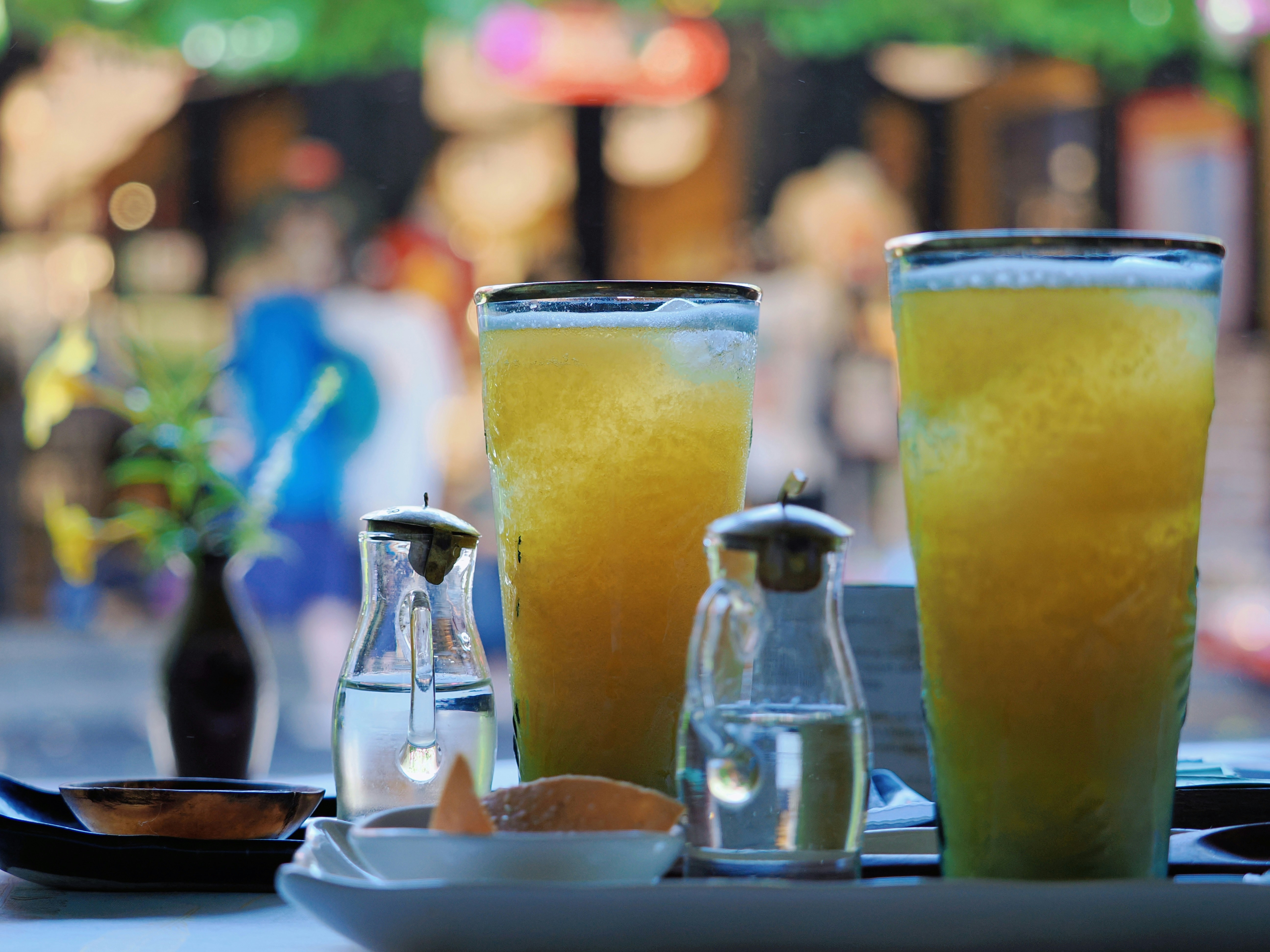 Two tall glasses of refreshing yellow beverage with condiments.
