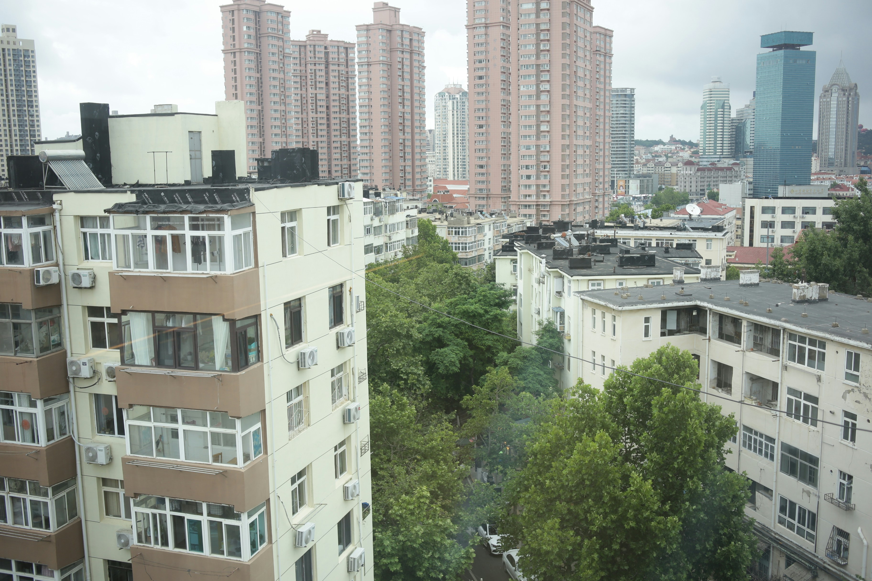 Prédios residenciais altos e árvores vistos do alto de um apartamento