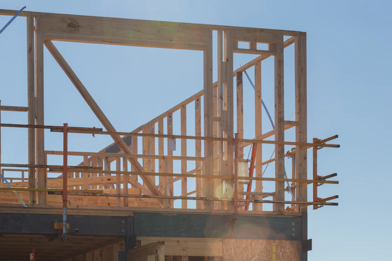 New building's timber framework against a clear blue sky