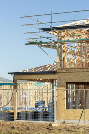 New house construction with wooden framing and scaffolding, showing the early stage a home reaches after a builder pulls a permit