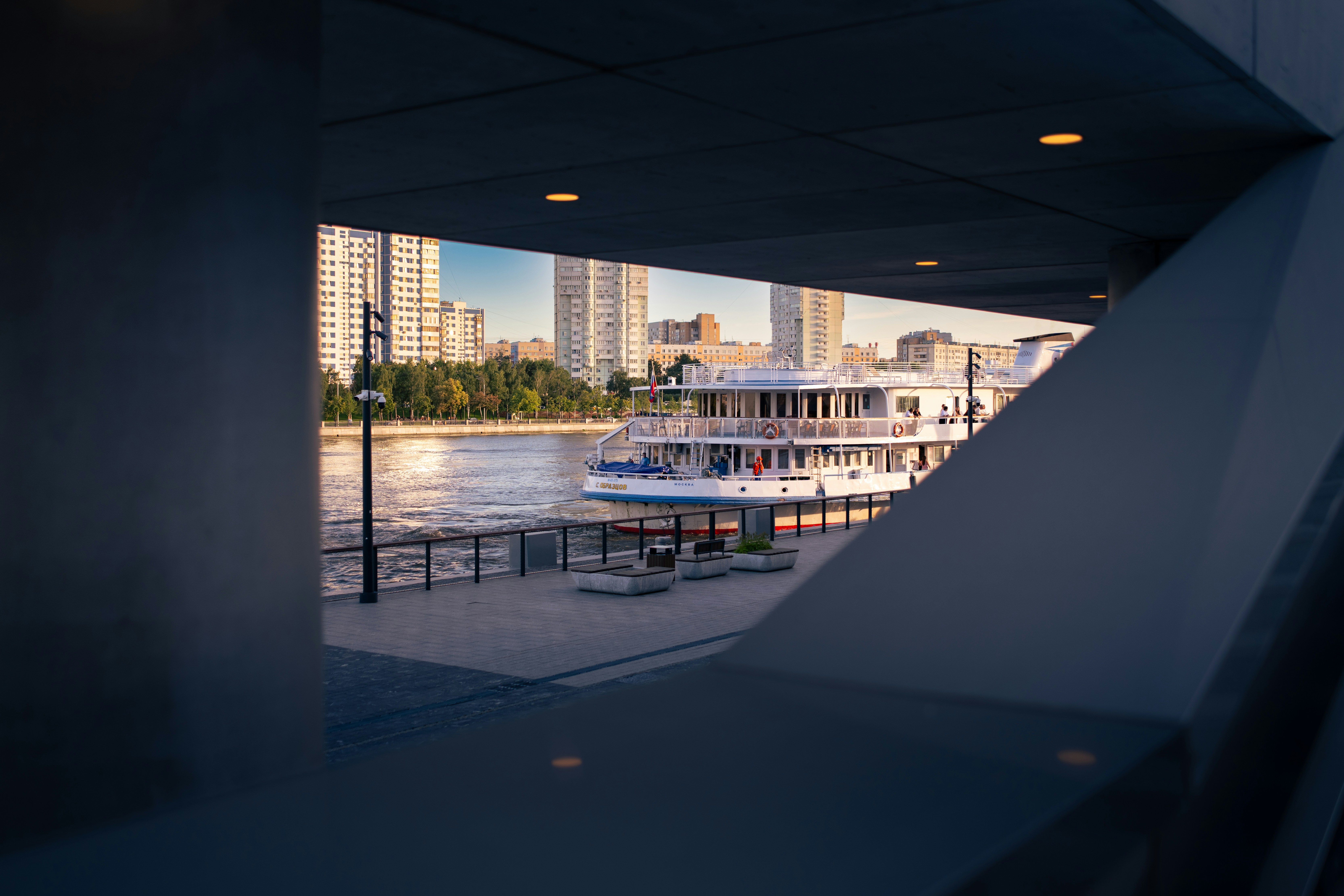 Riverboat docked near modern buildings, viewed through a frame.