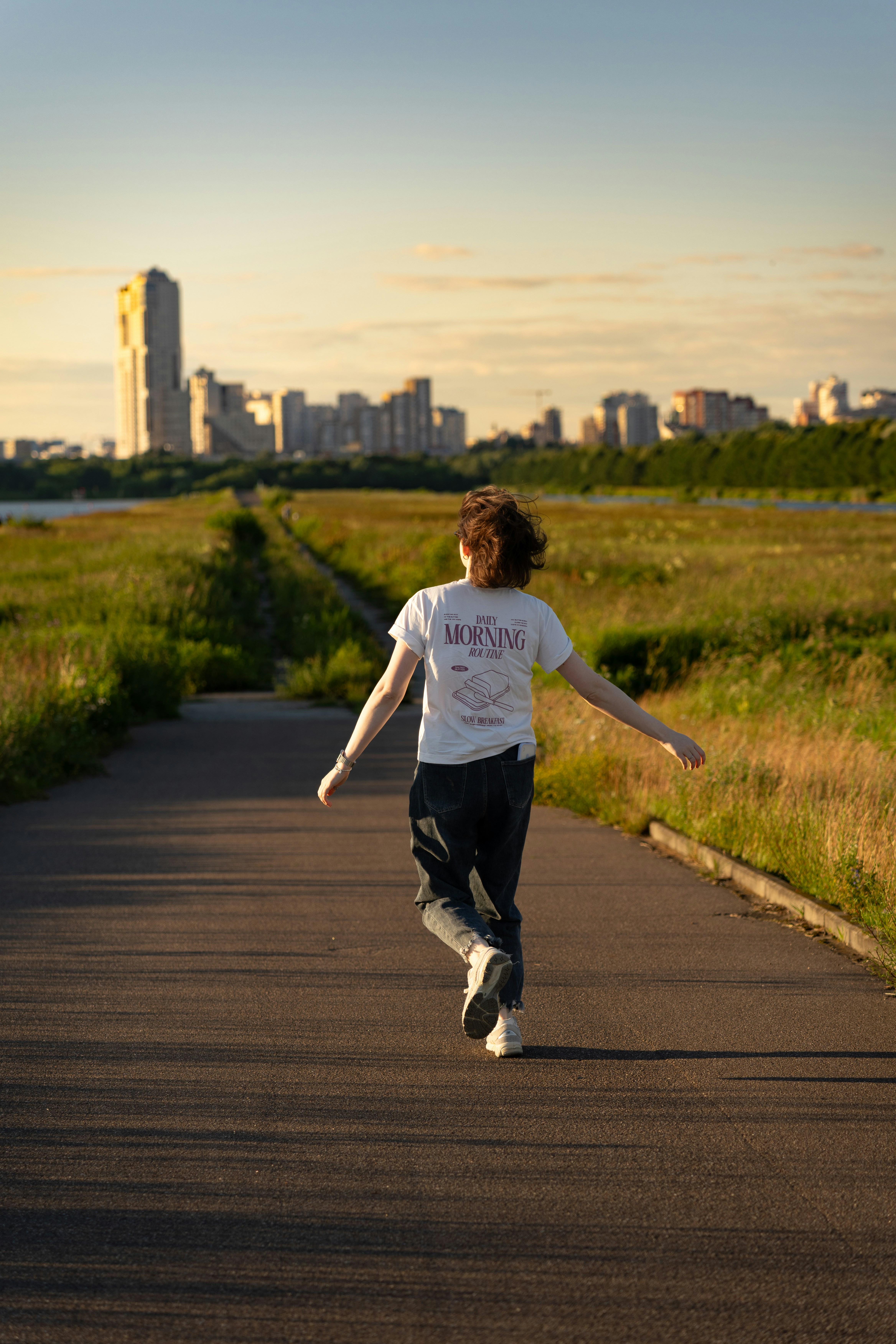 Person running on a path towards a distant city skyline.