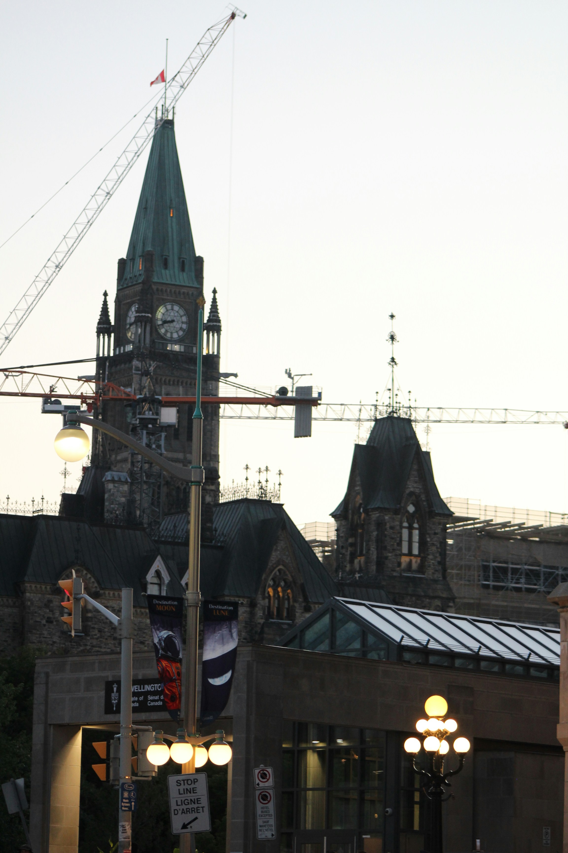 Parliament building with construction cranes and streetlights at dusk