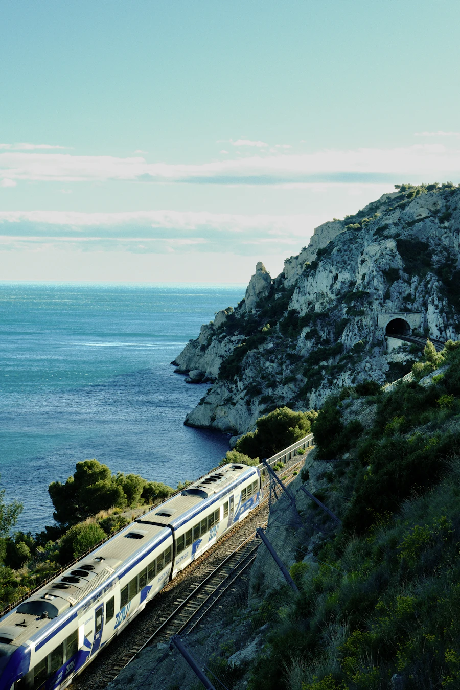 Un train circule le long de voies ferrées au bord de l'océan, lumière du soir, ambiance côtière
