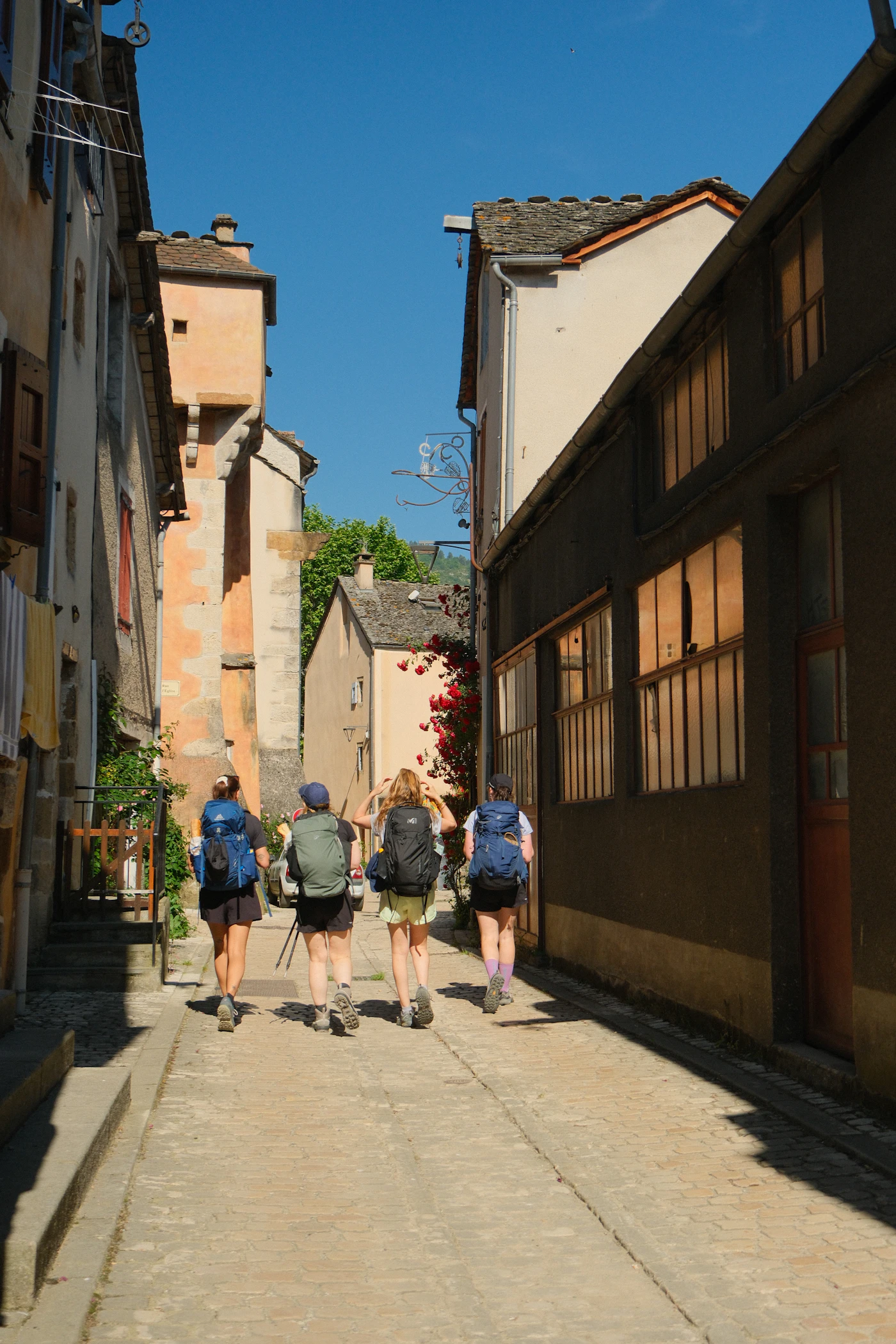 Four friends walking a sunny old-town lane