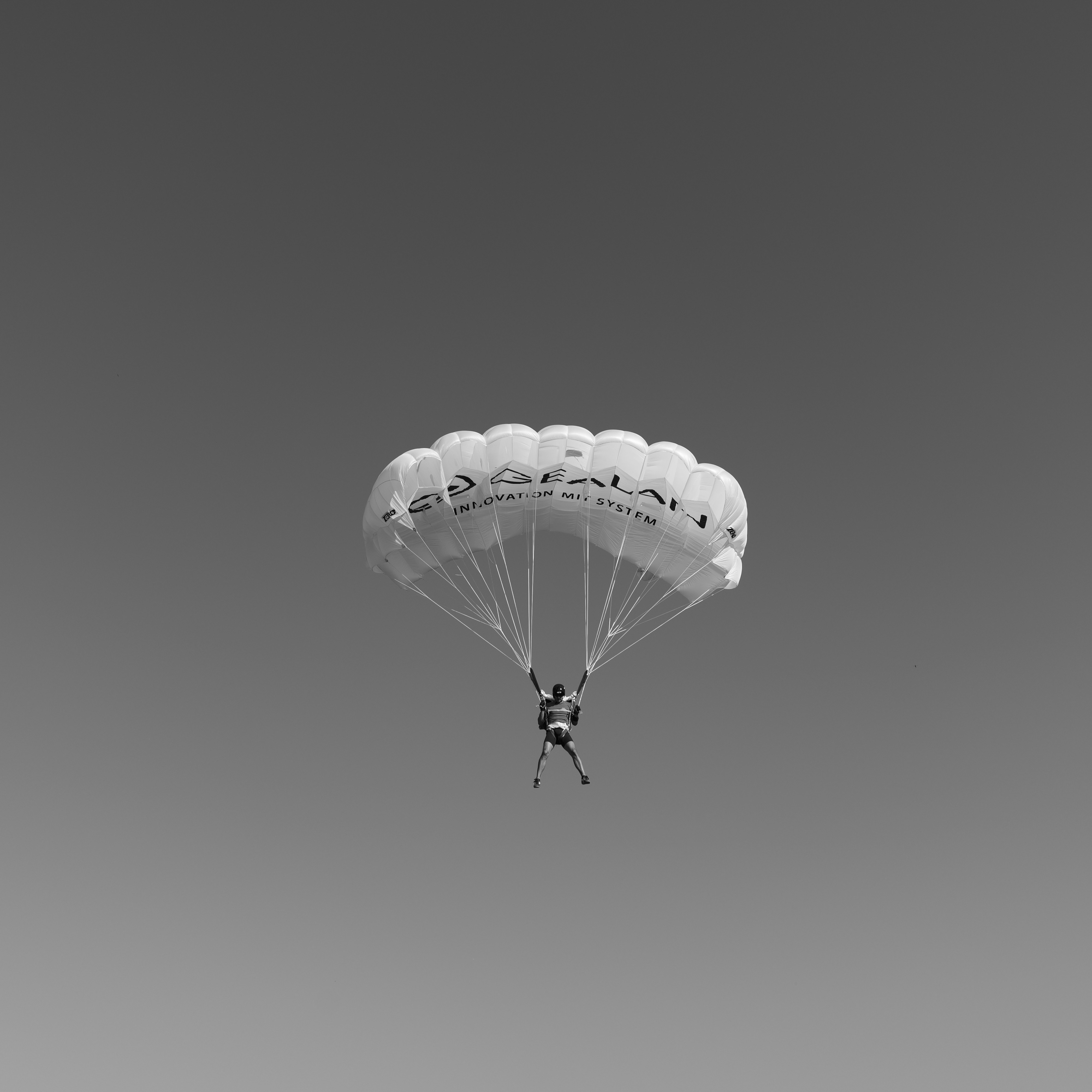 Skydiver with parachute against a clear sky.