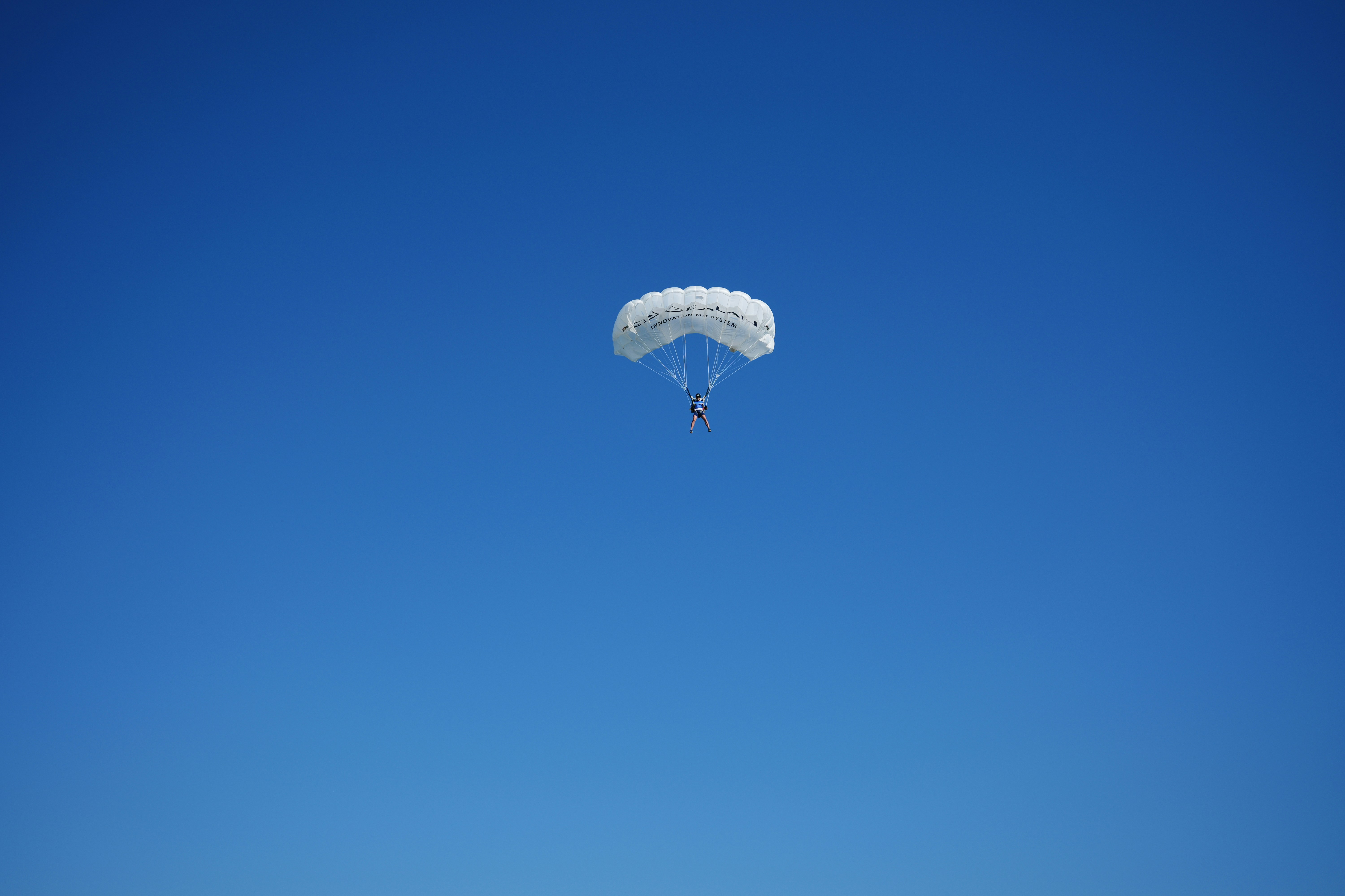 A person parachuting against a clear blue sky.