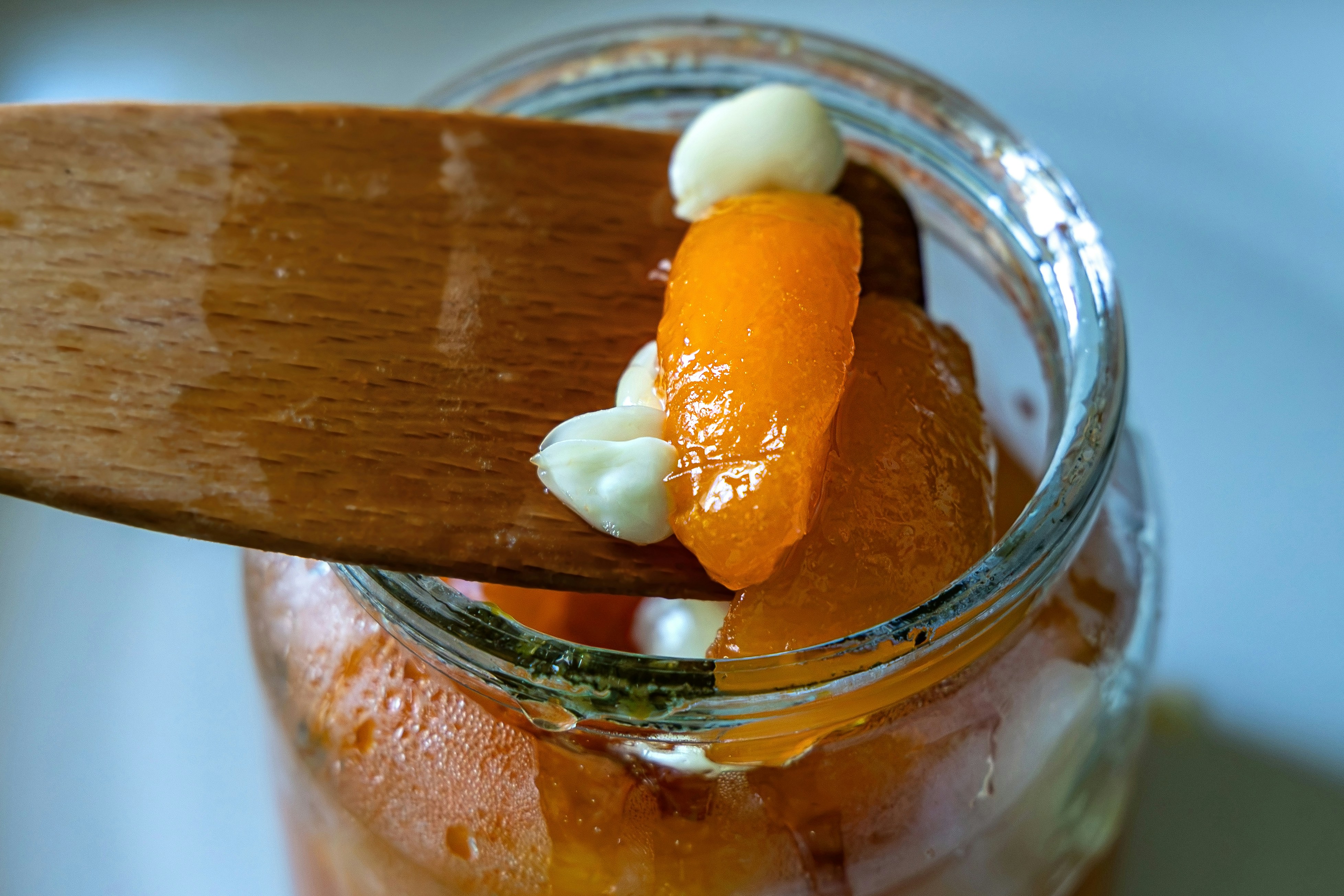 Wooden spoon scooping fruit and cream from a glass jar.