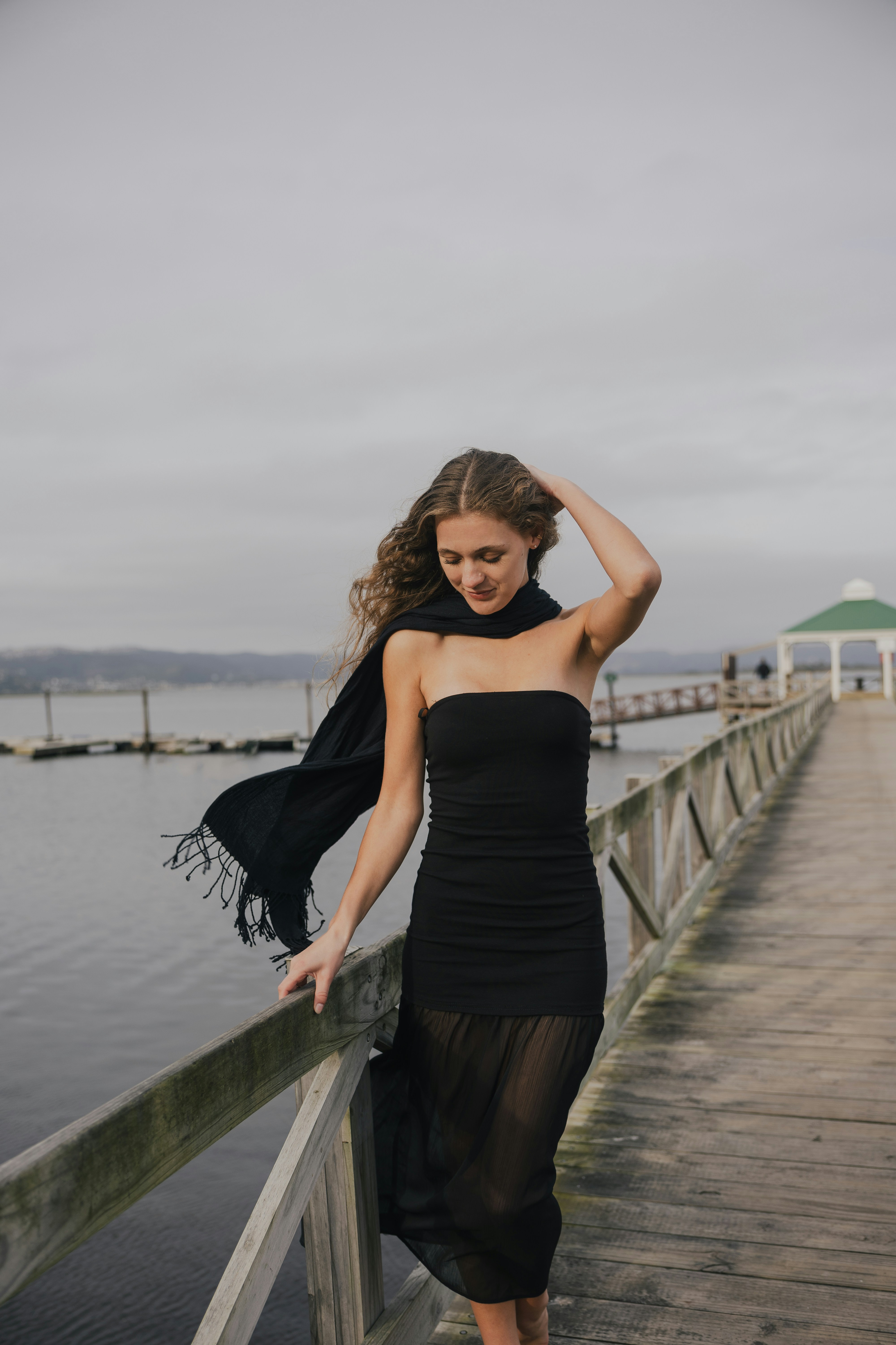 Woman in black dress and scarf walks on a pier