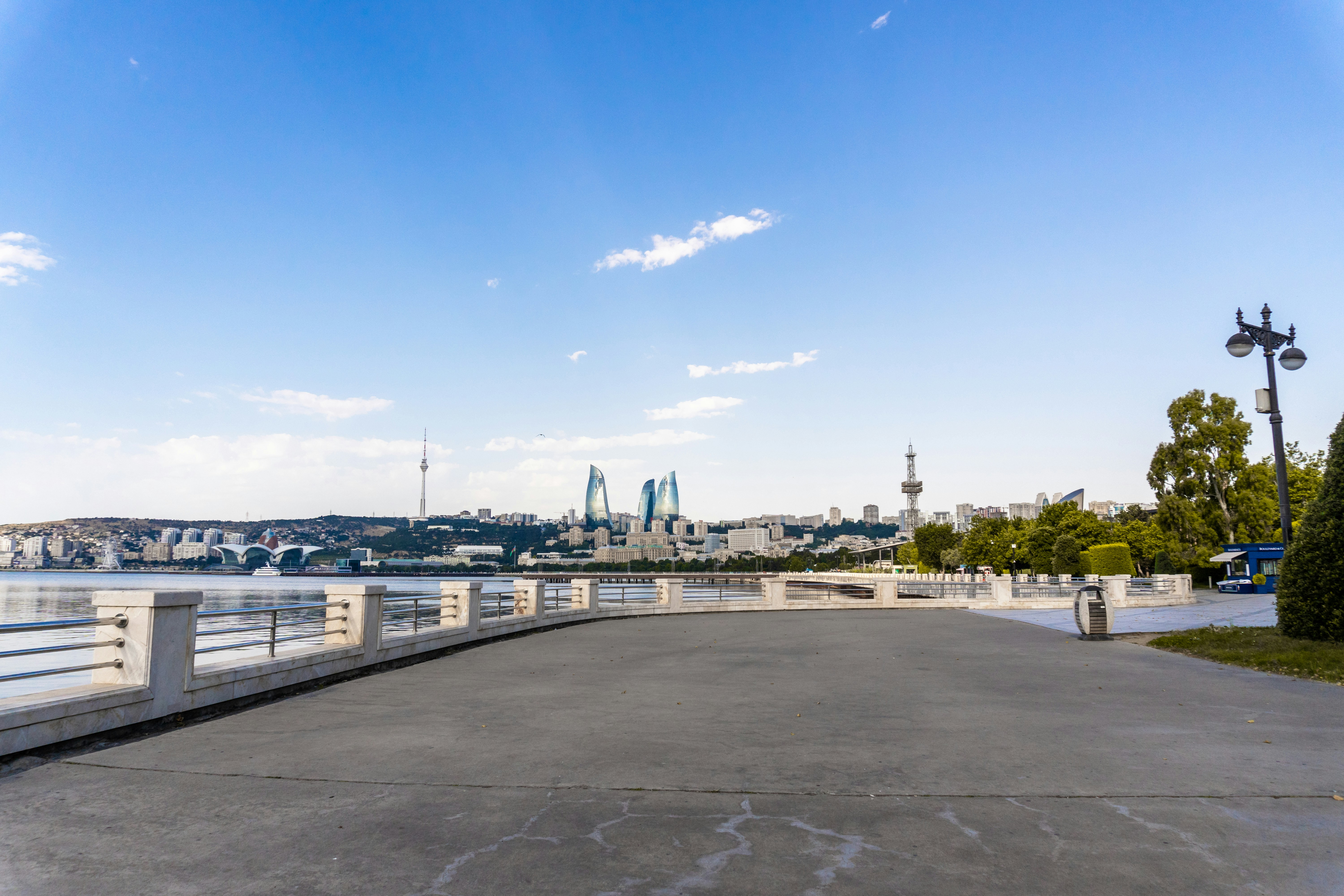 A scenic promenade along the bay with a city skyline.