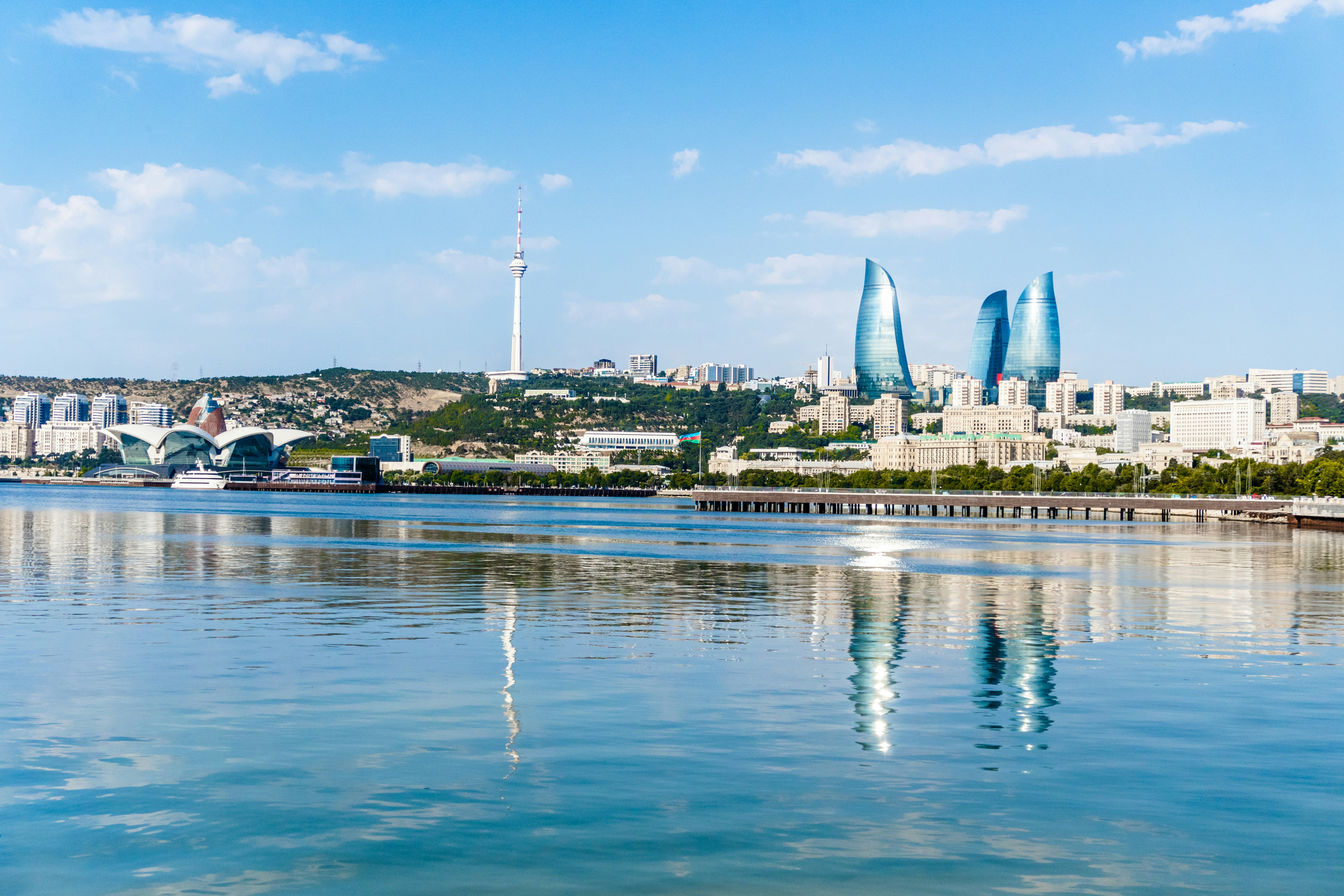 Modern city skyline with distinctive towers reflecting in calm water