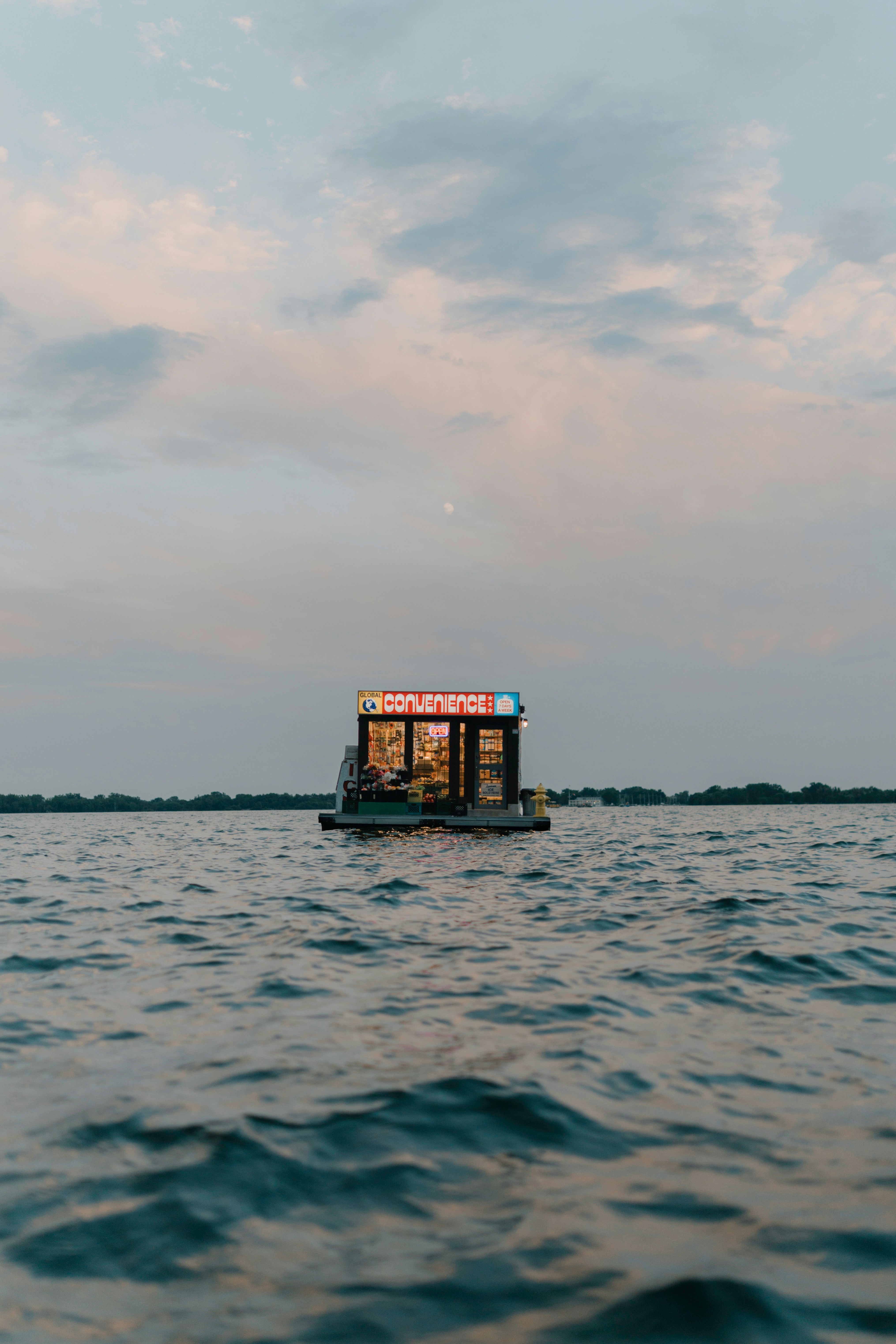 Illuminated floating bar on calm water under a twilight sky