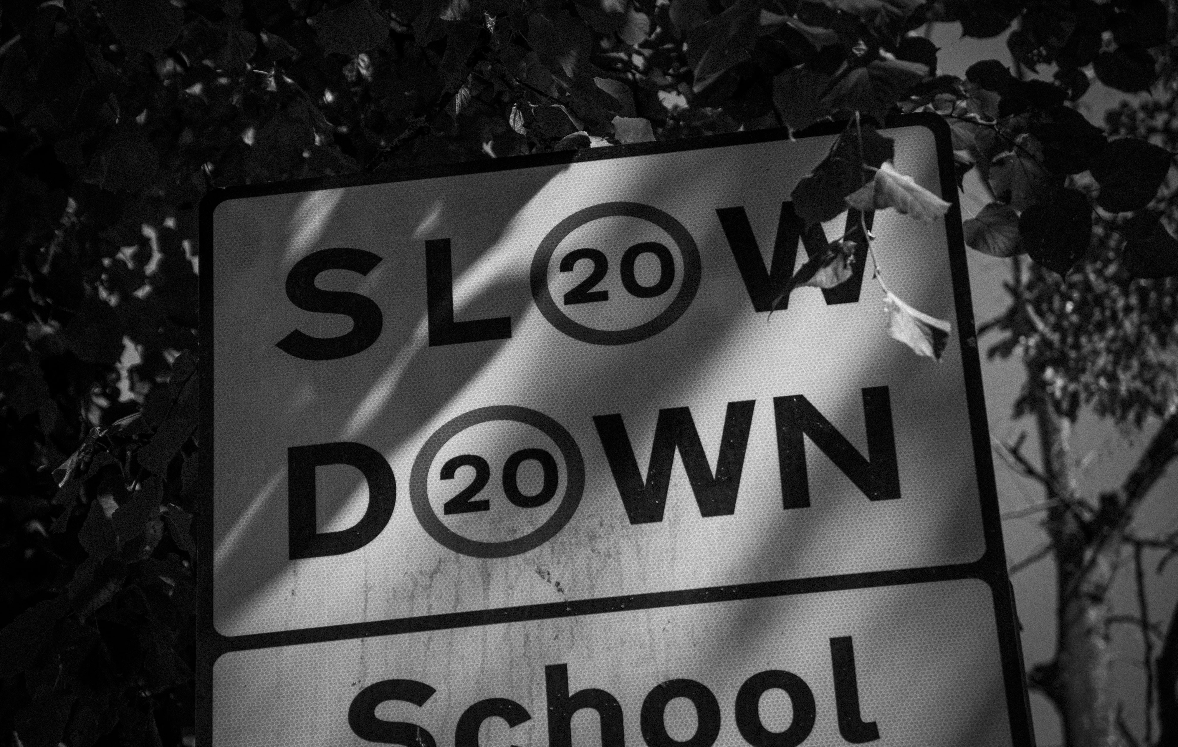 Black and white "slow down 20 school" sign with shadows.