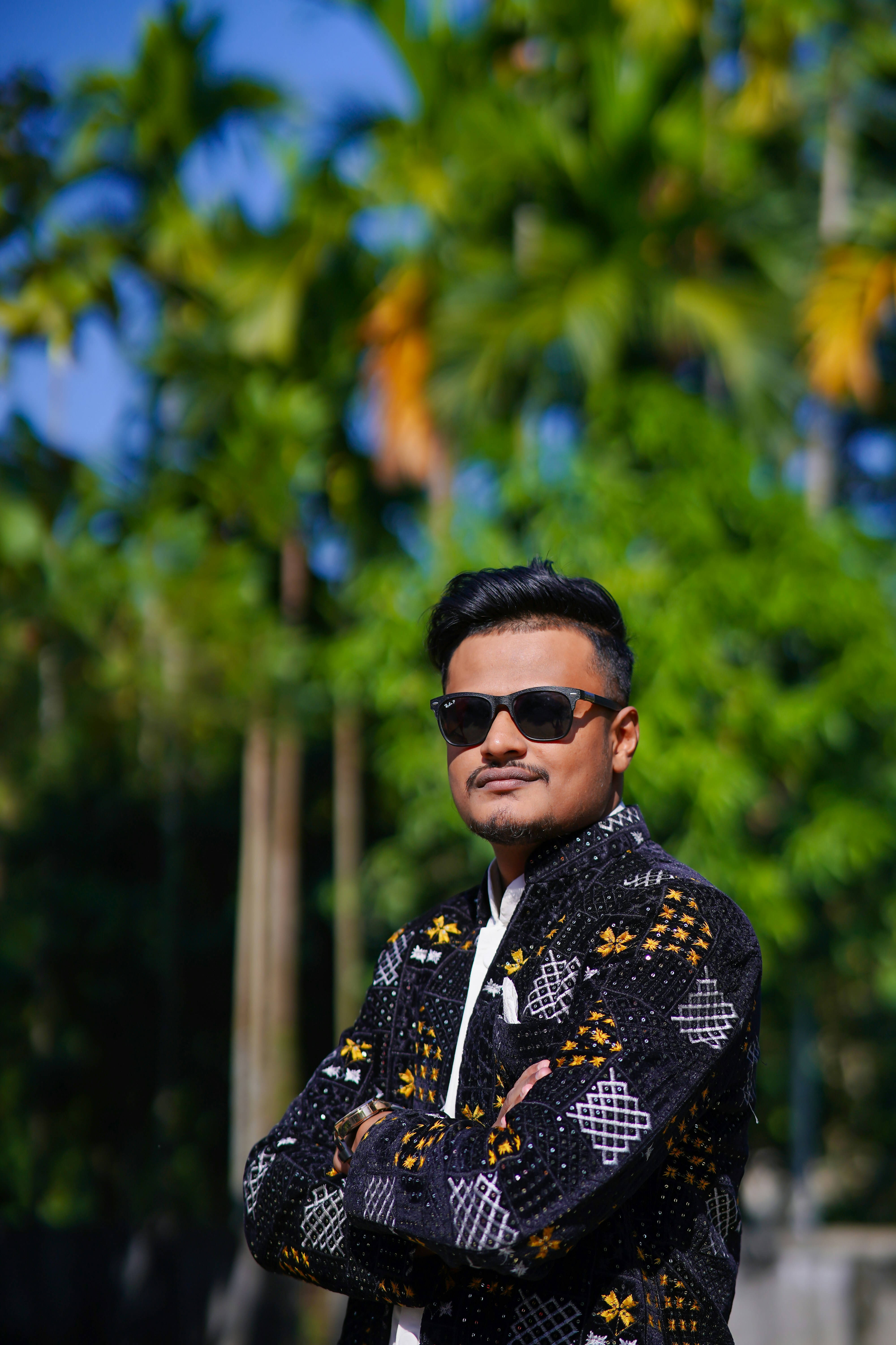 Mann in schwarz gemusterter Jacke und Sonnenbrille draußen