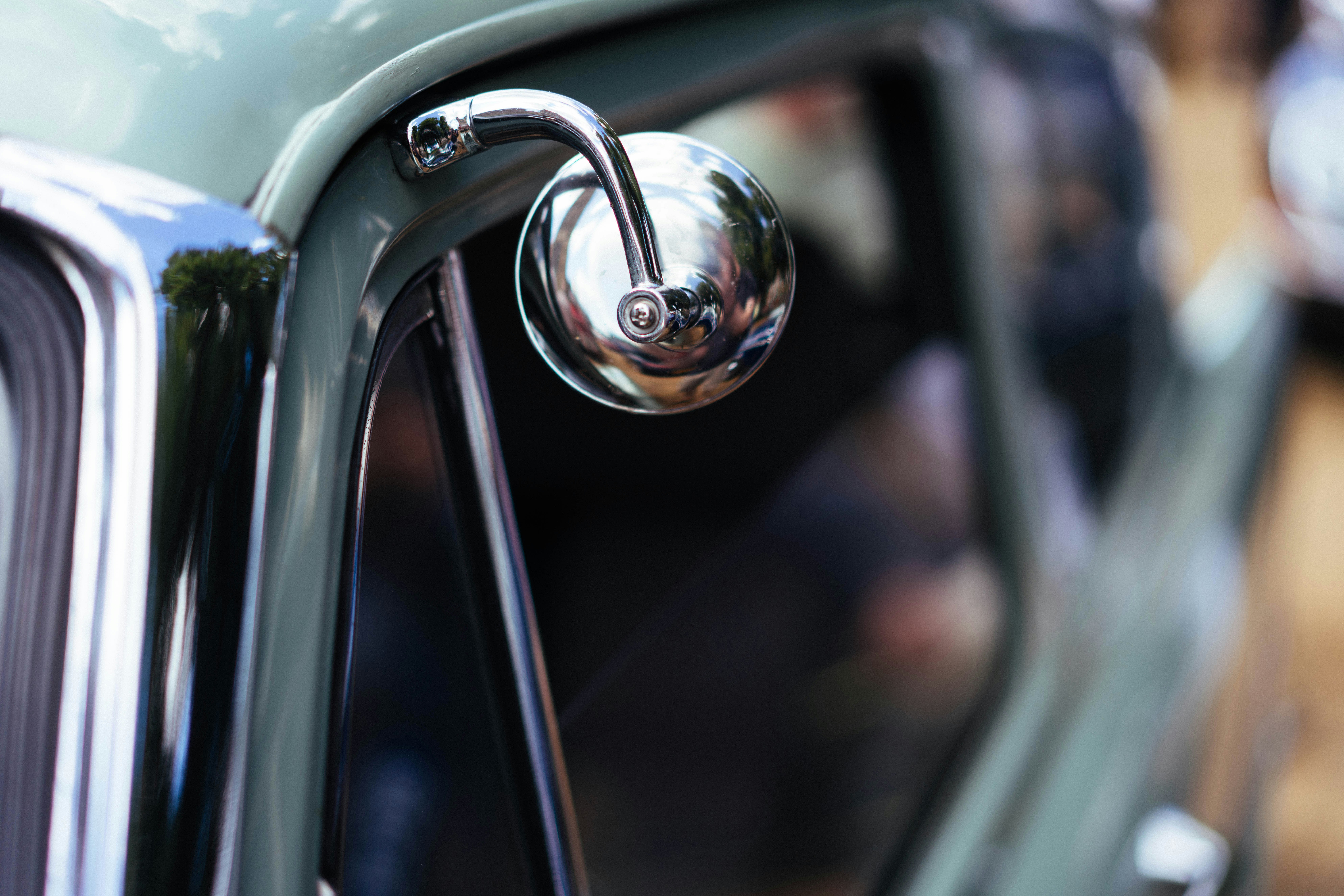 A chrome side mirror on a vintage light green car.