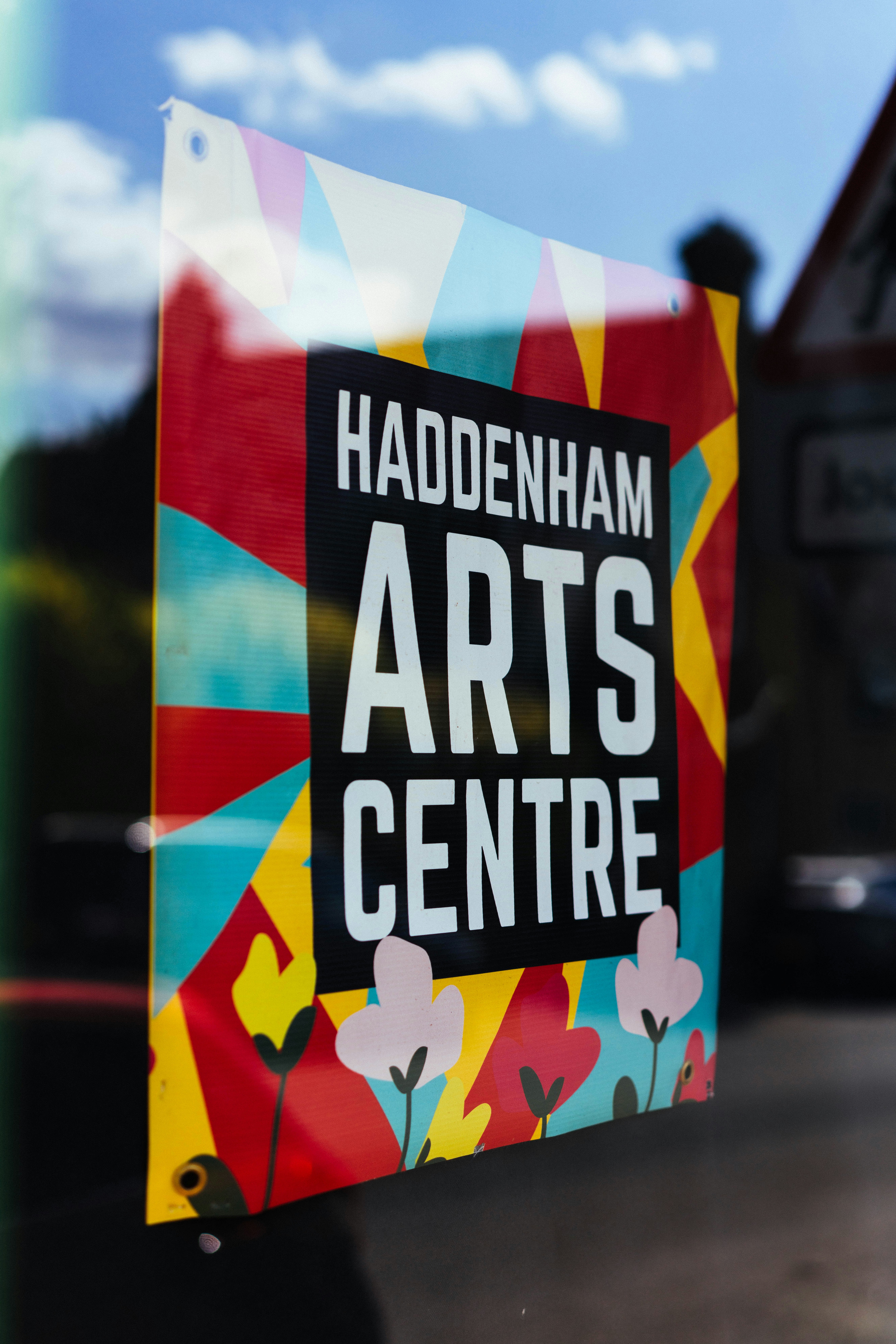 Colorful haddenham arts centre banner displayed in a window.