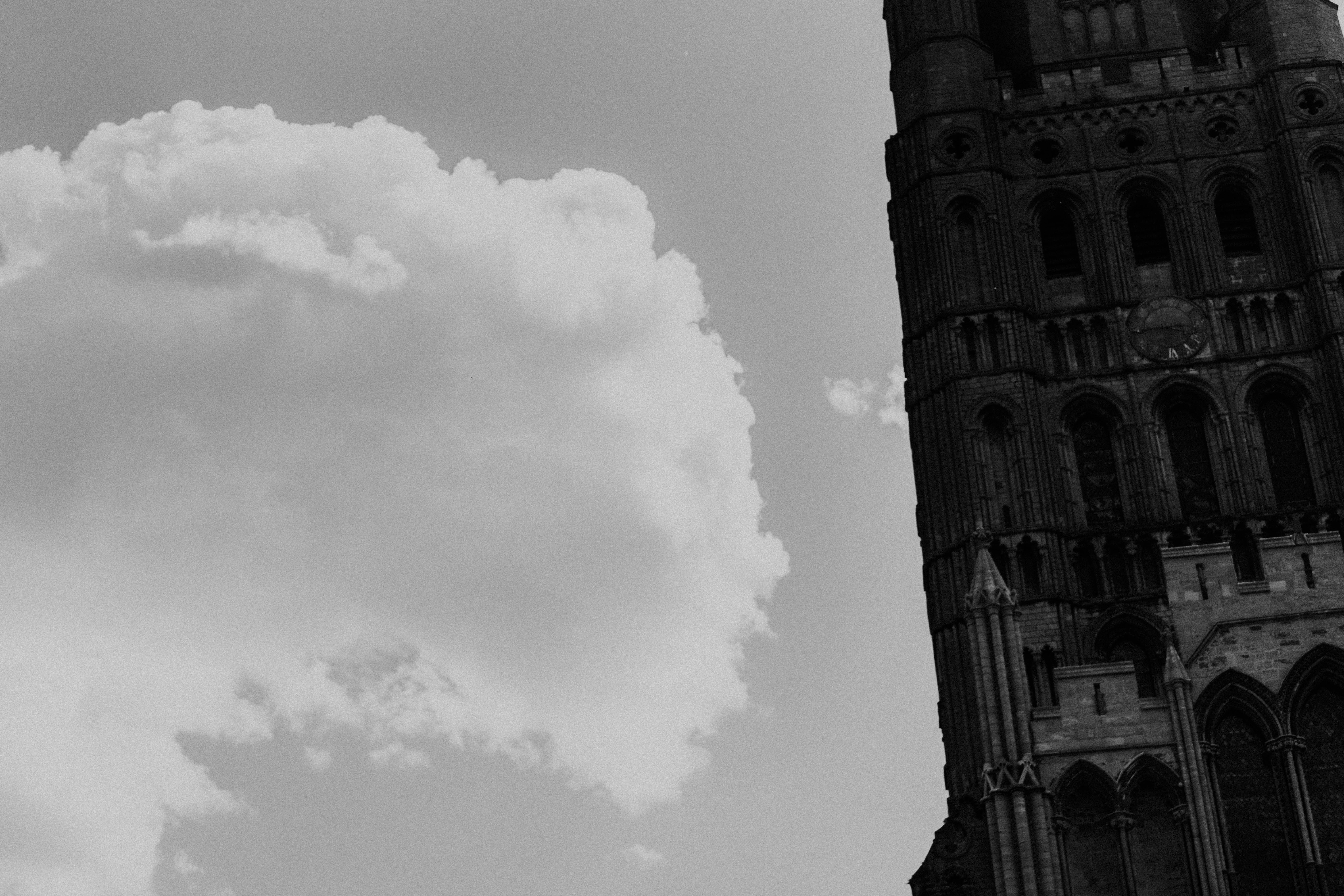 Historic tower and fluffy cloud against a bright monochrome sky.